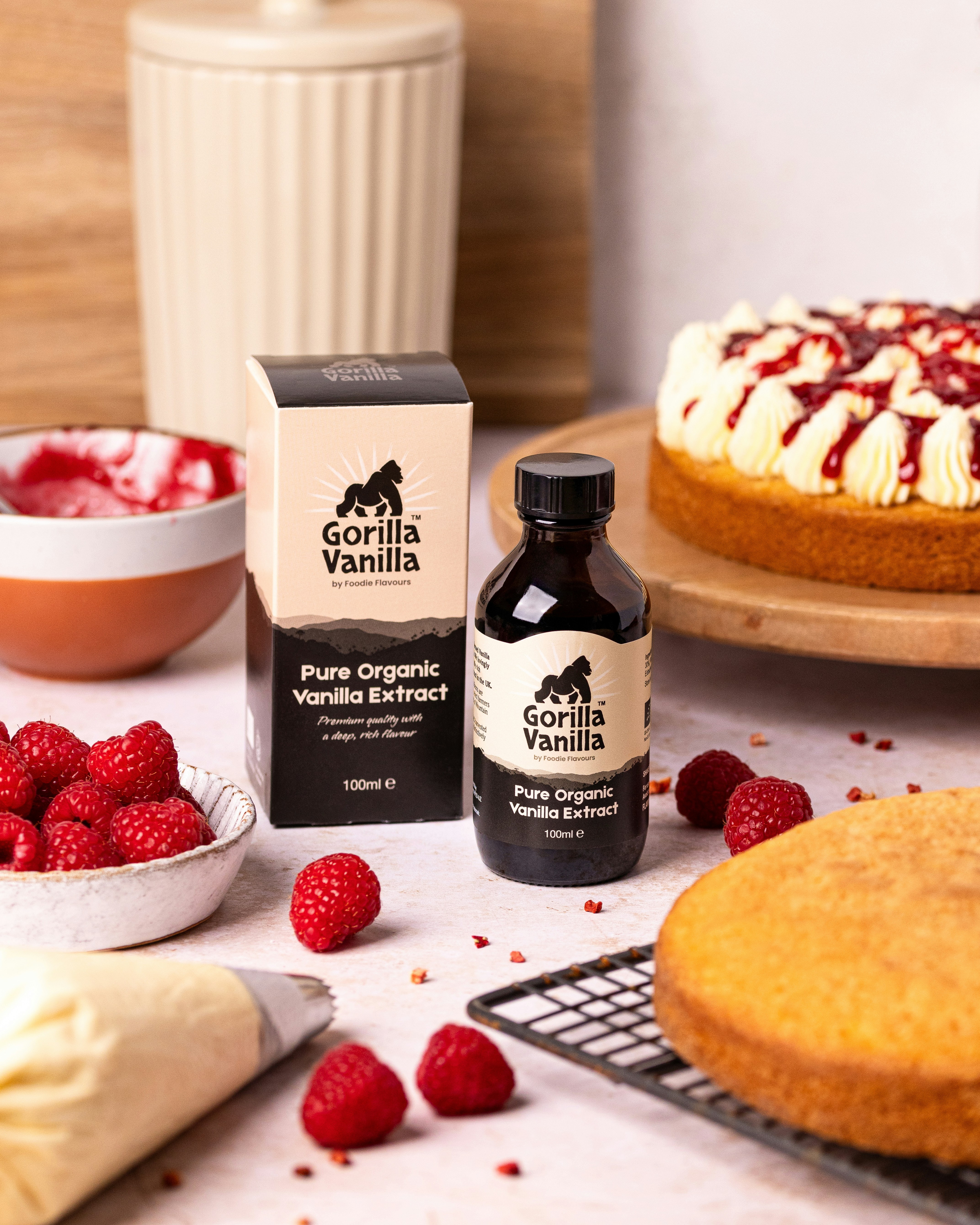 Vanilla extract bottle with cake and raspberries.