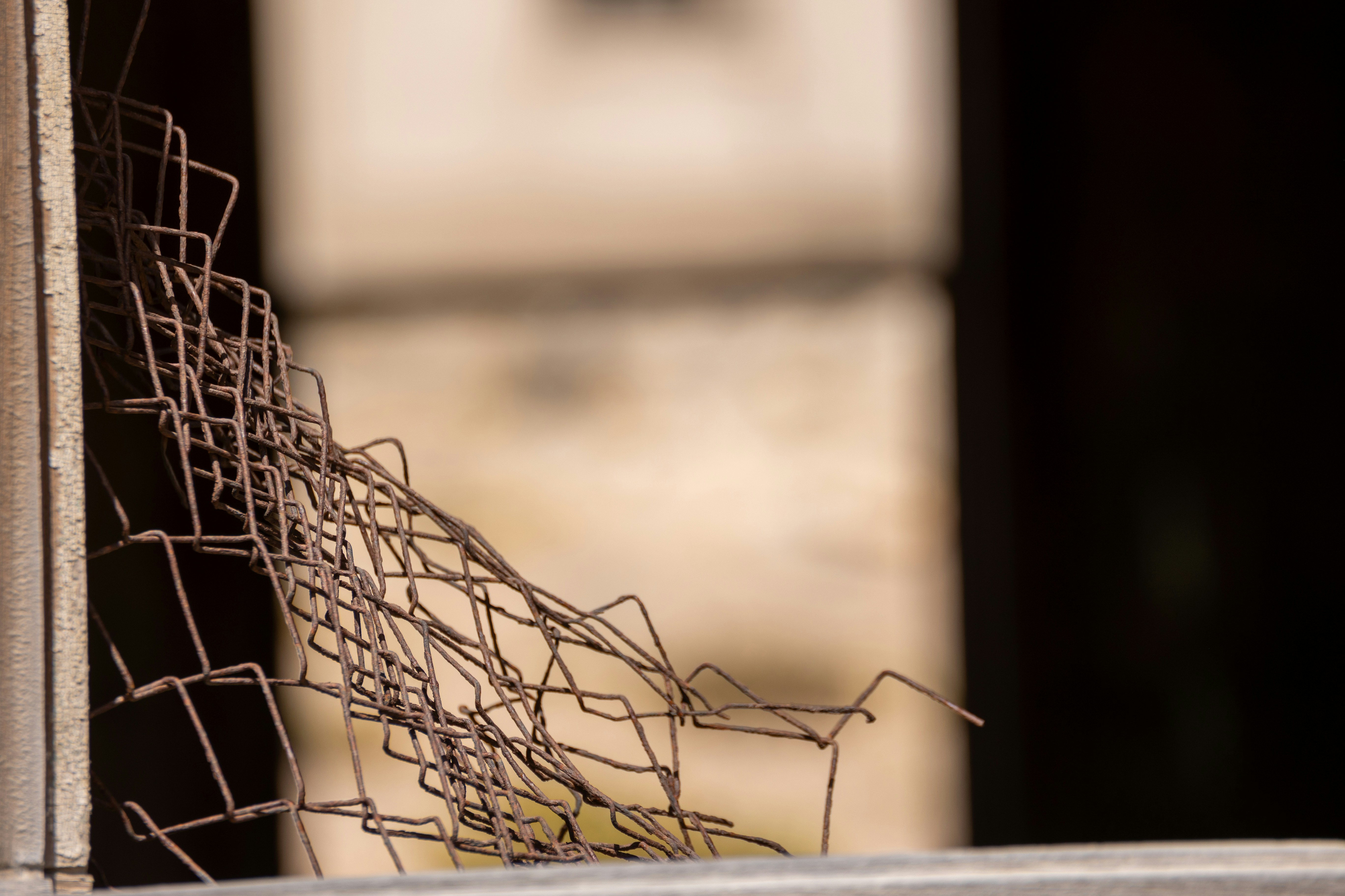 Damaged rusty metal fence with blurred background.