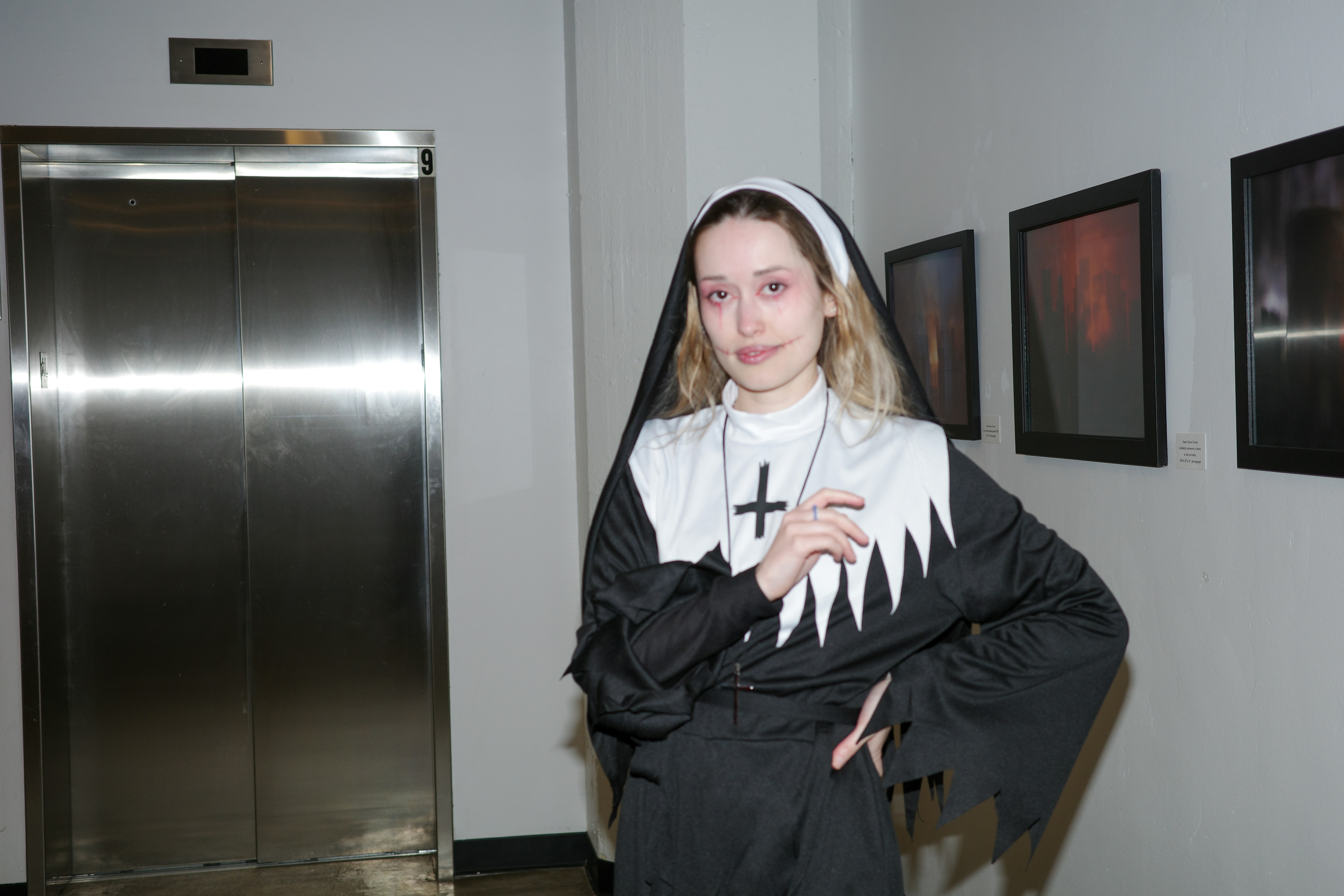 A woman dressed as a nun stands by an elevator.