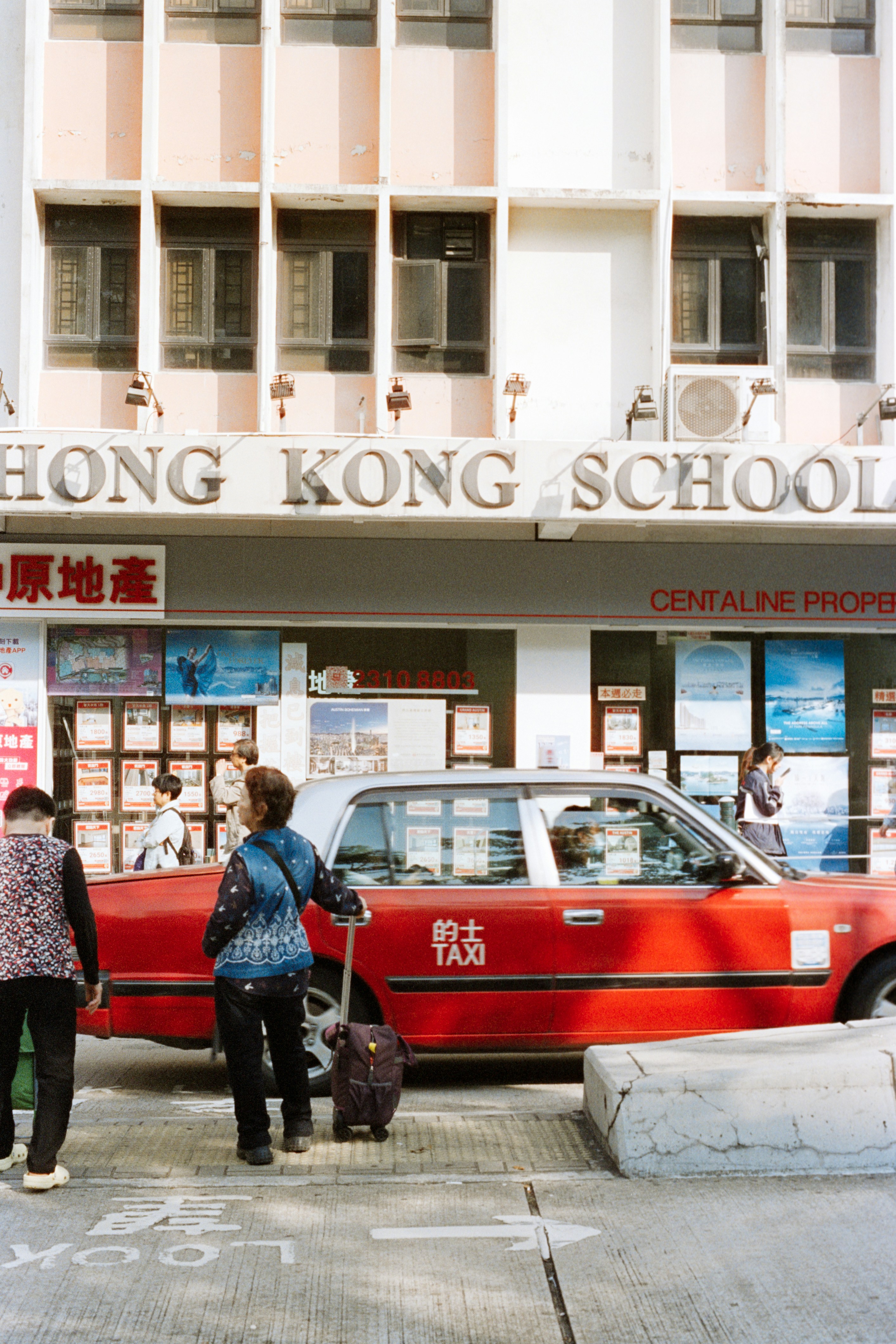 People and red taxi outside hong kong school