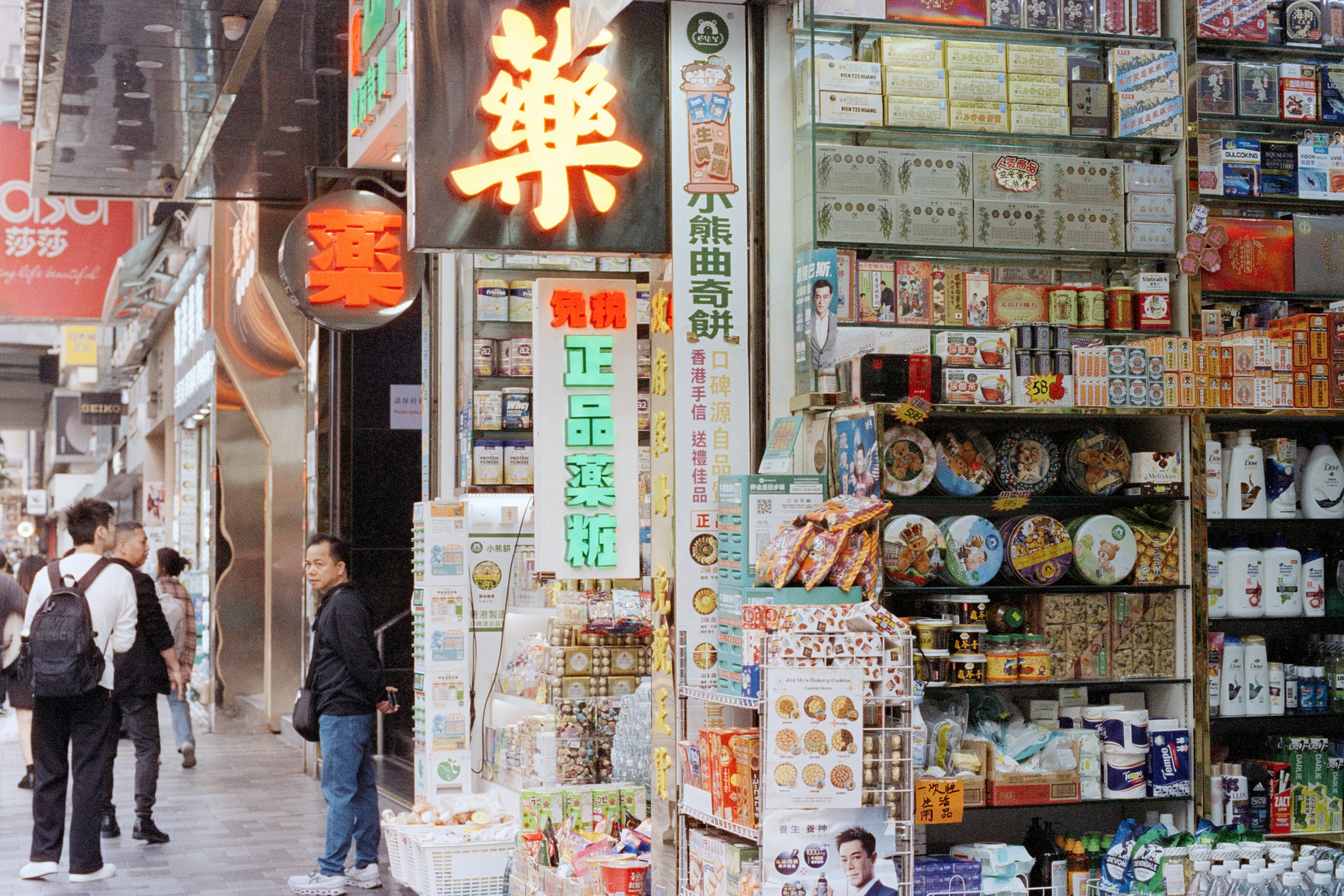 A busy street with shops displaying many products.