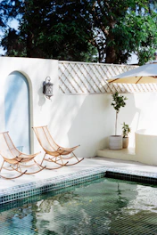 Two rocking chairs beside a swimming pool.