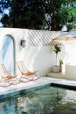 Two rocking chairs beside a swimming pool.