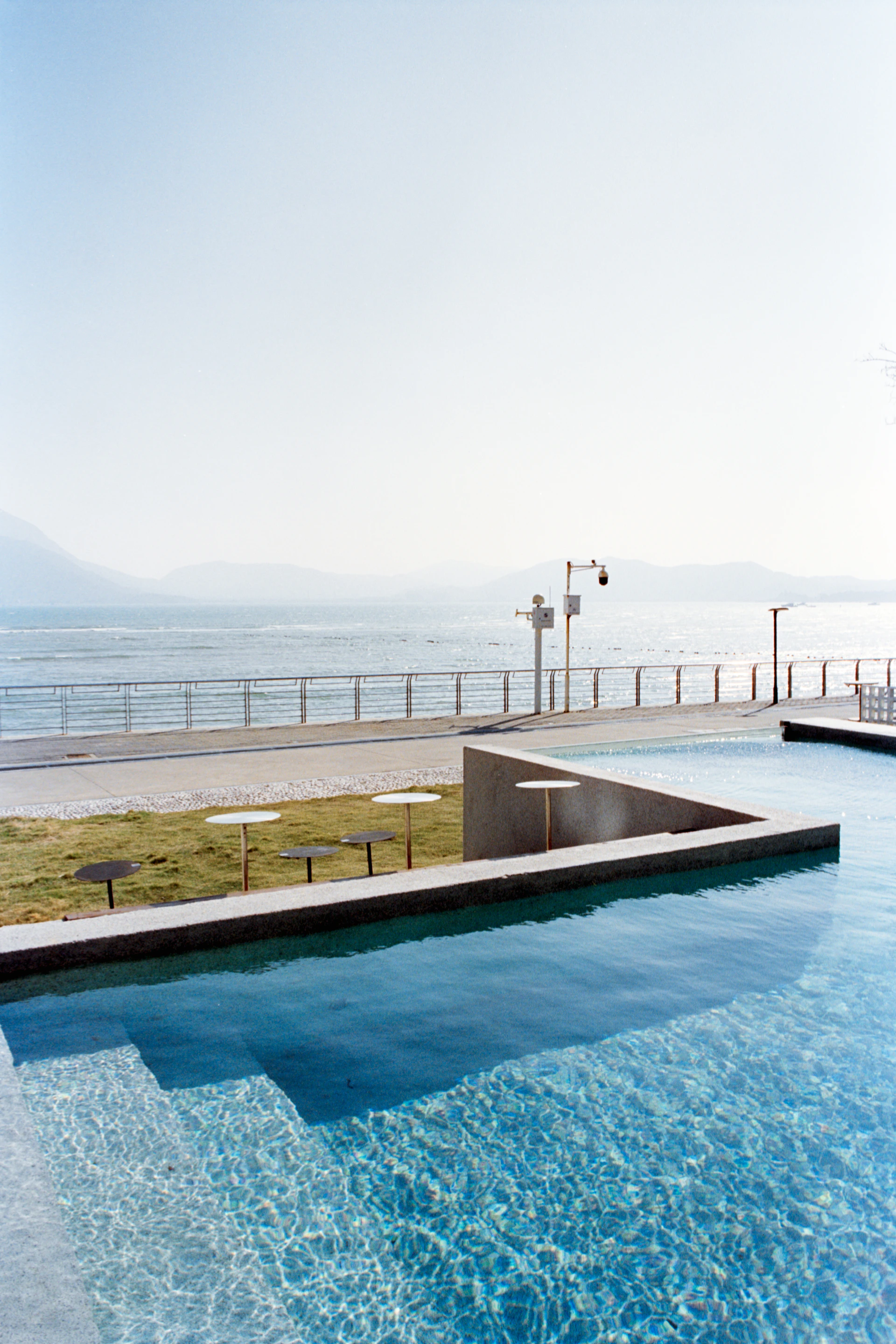 Infinity pool overlooking a calm ocean and distant mountains.