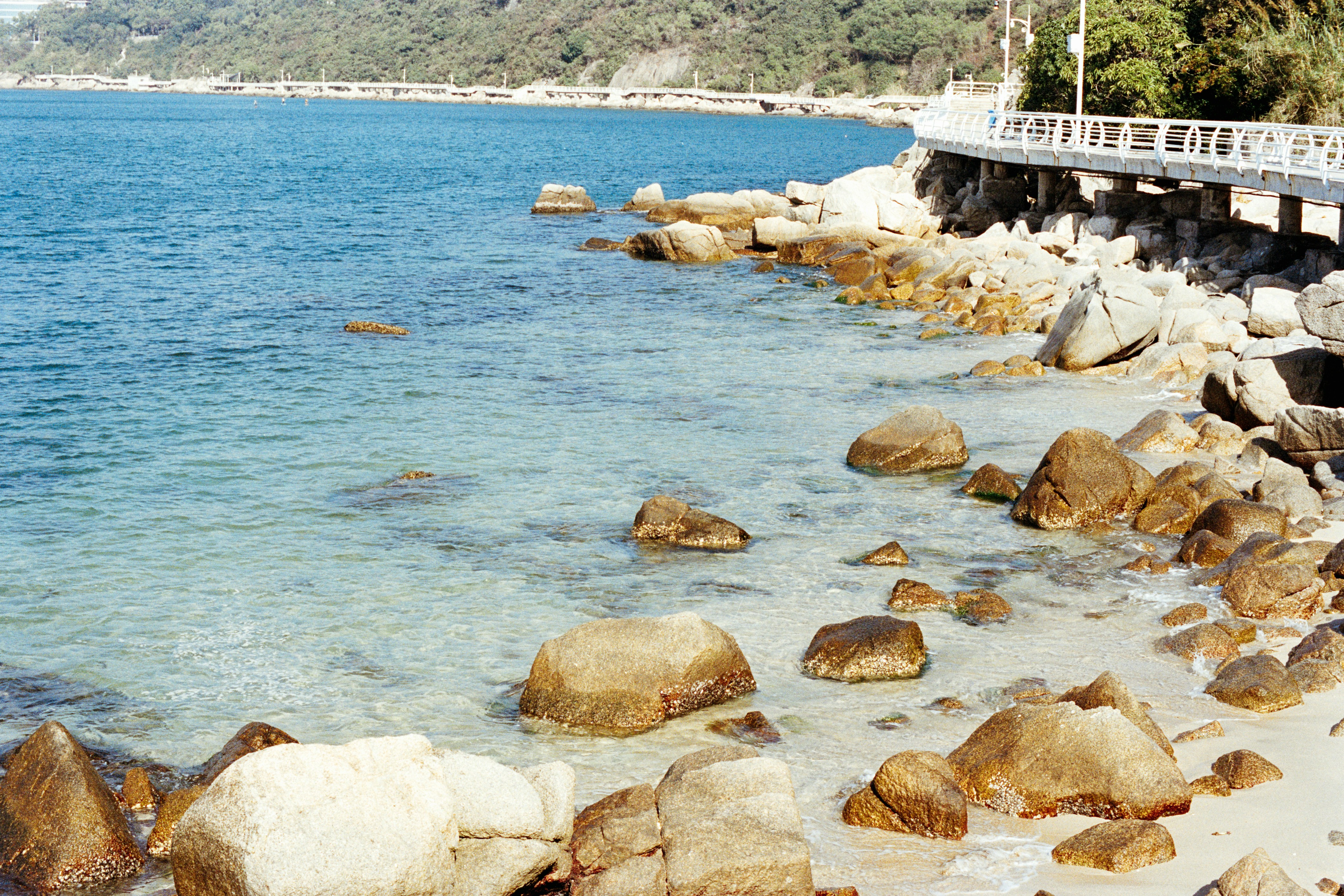 Playa rocosa con aguas turquesas claras y un paseo. foto – Imagen de ...