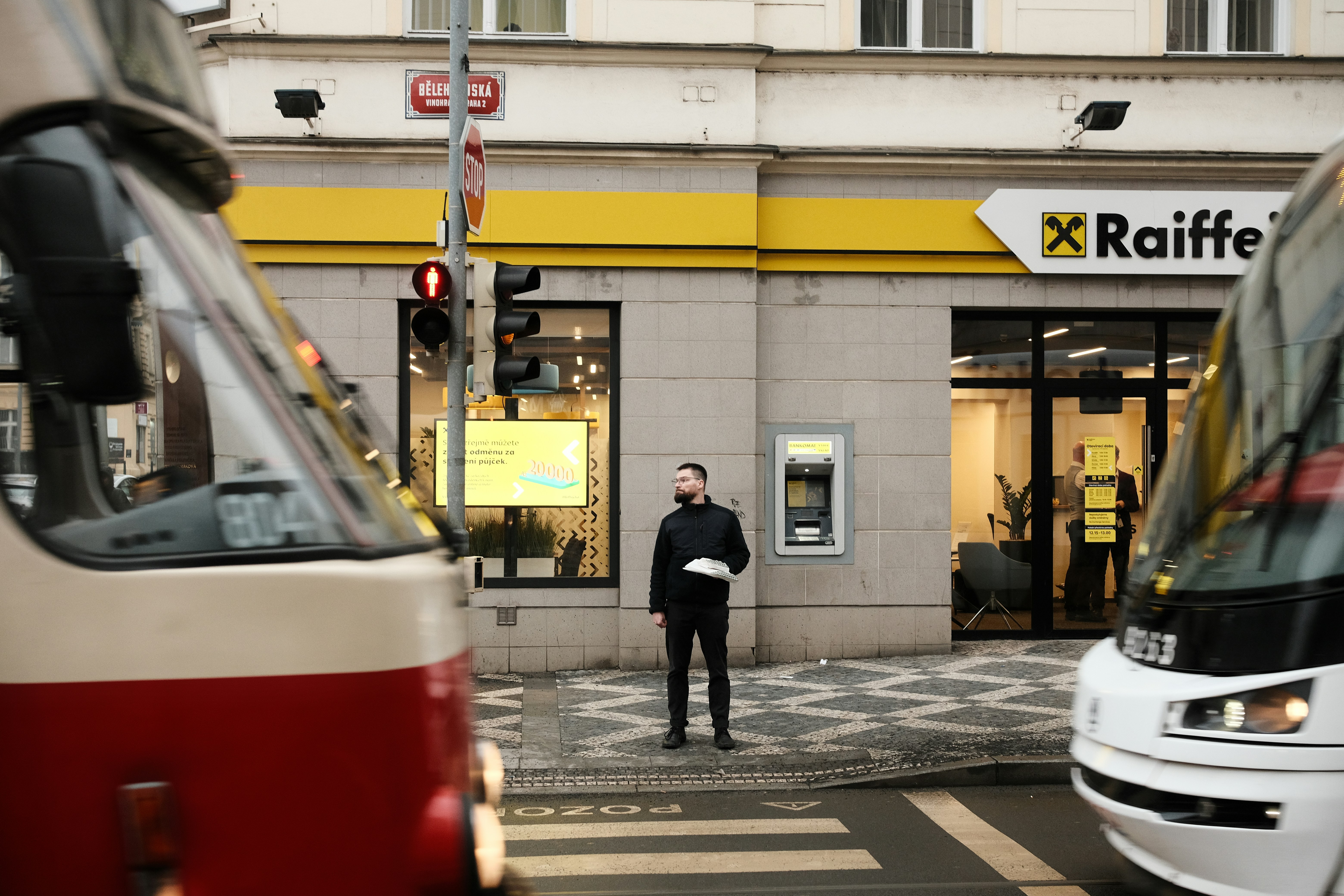 Mann steht zwischen zwei Straßenbahnen an einem Zebrastreifen.
