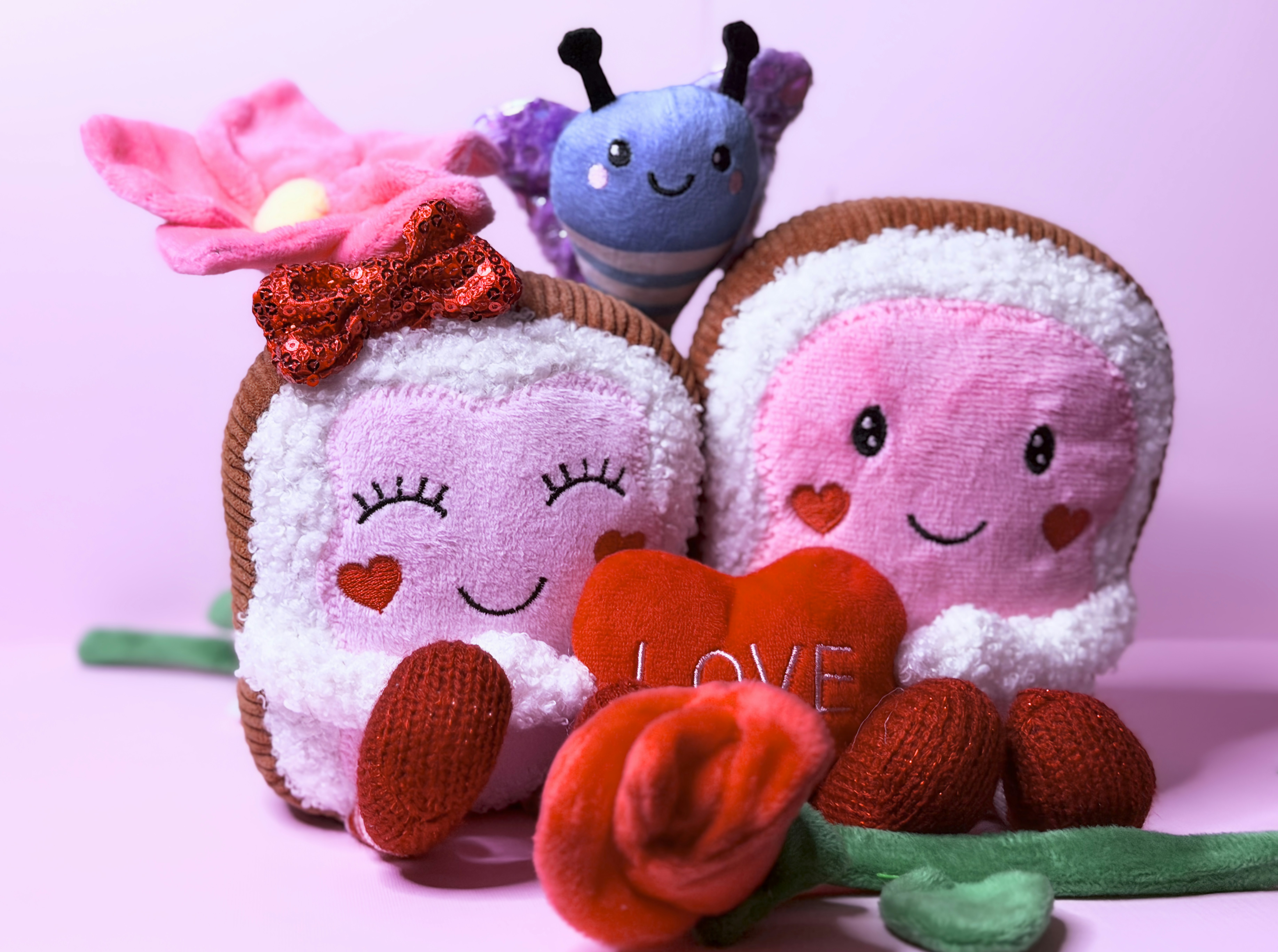 Zwei Plüschfiguren mit einer Blume und einem Herzen.