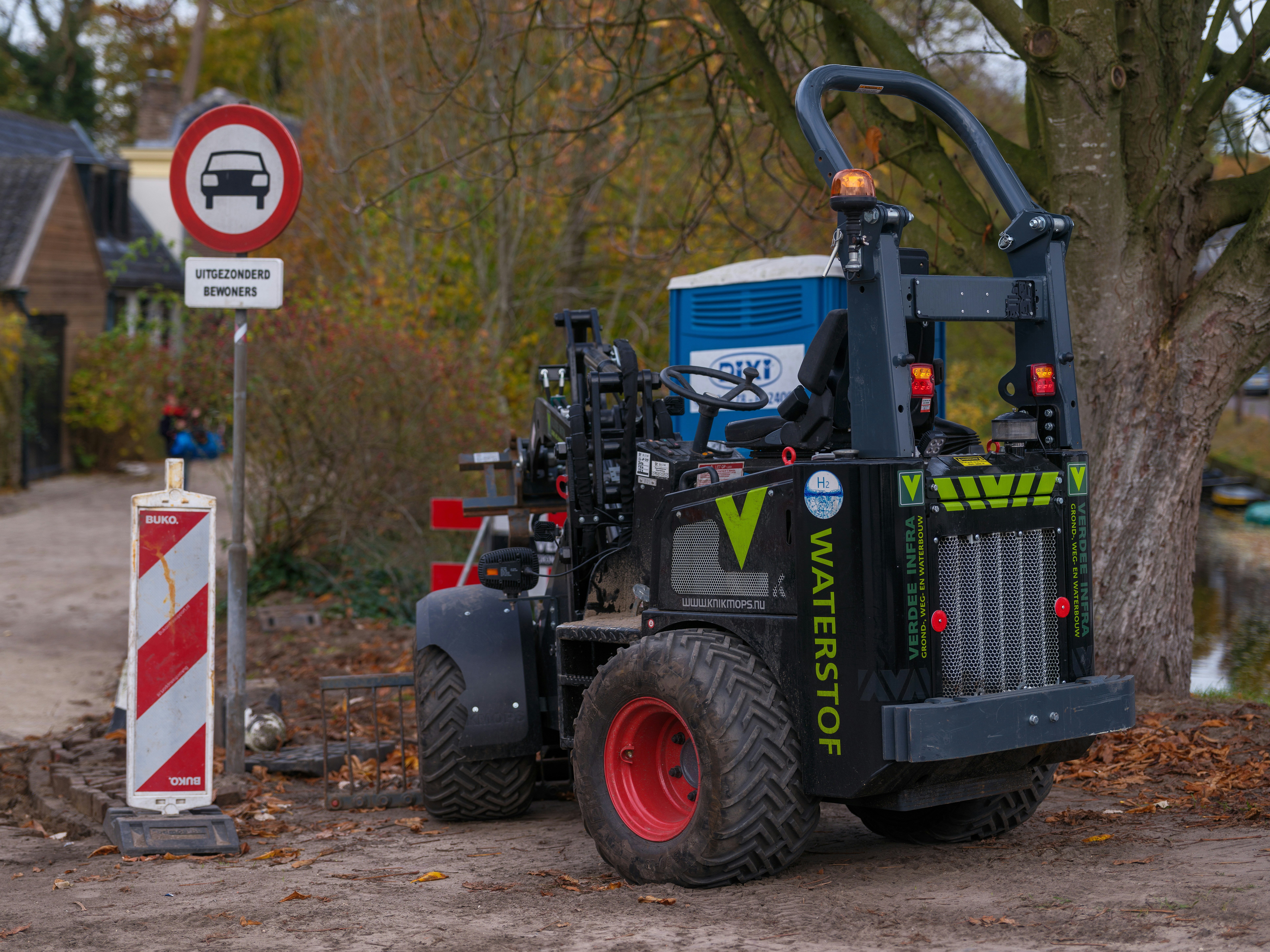 Construction vehicle parked near road signs and trees