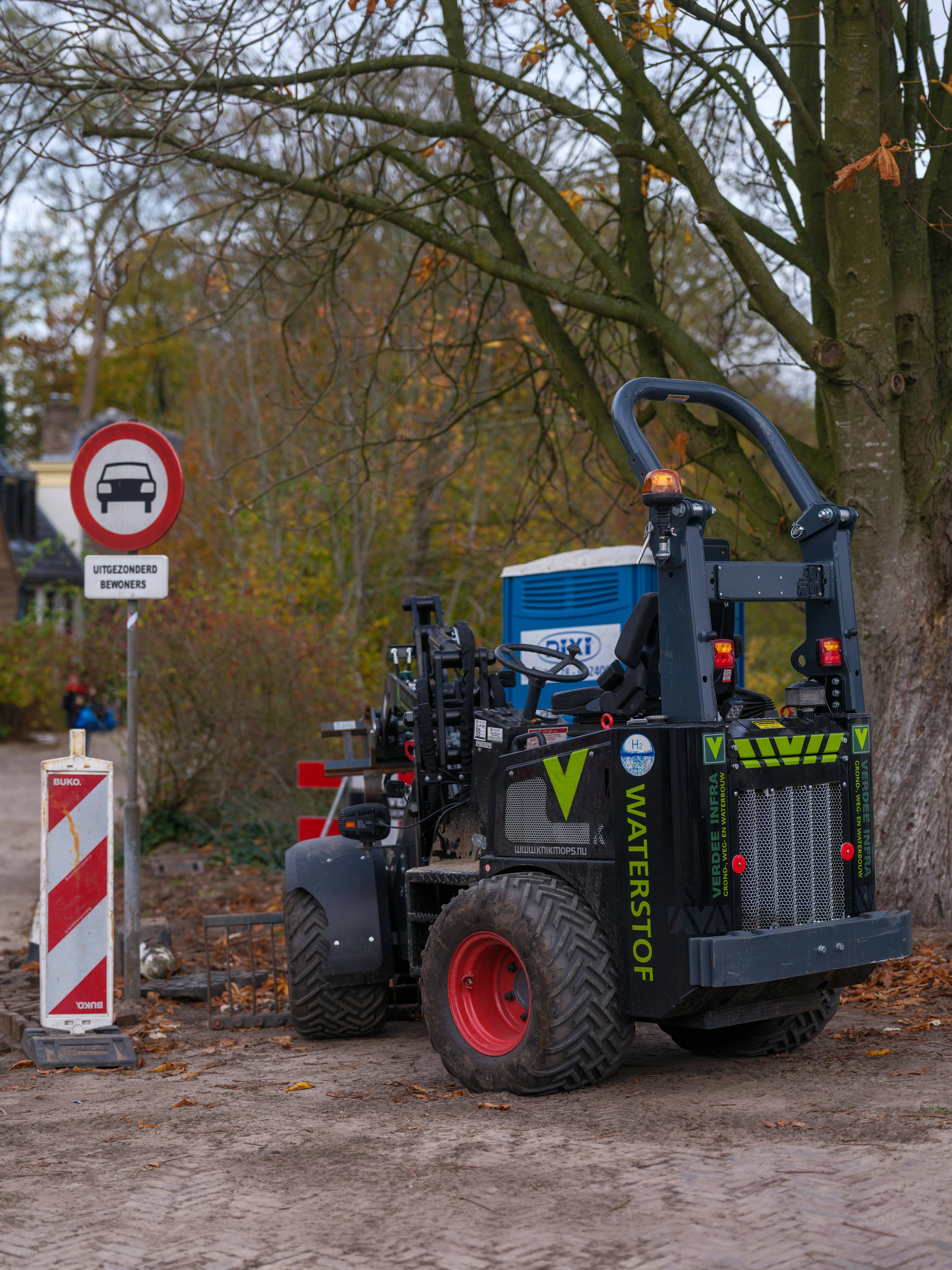 A small industrial vehicle parked near a road sign.