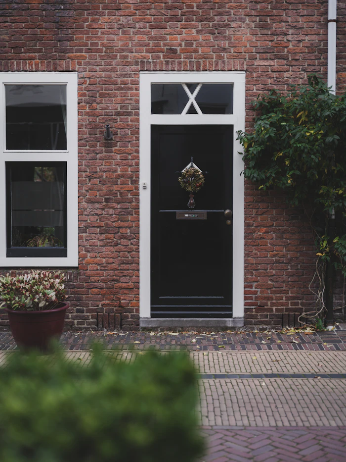 Black front door on a brick house with a wreath