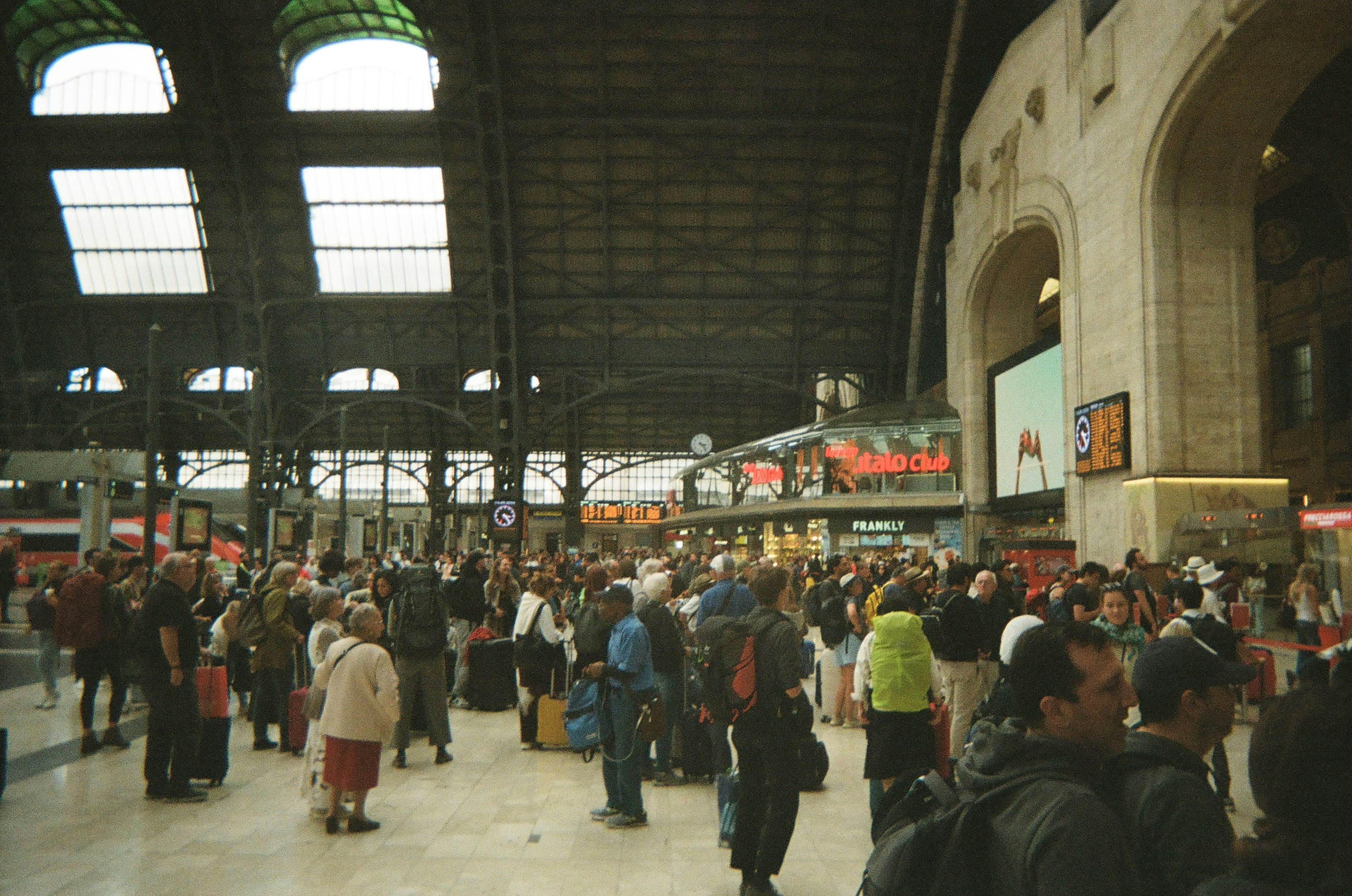 Crowded train station concourse with travelers and architecture.