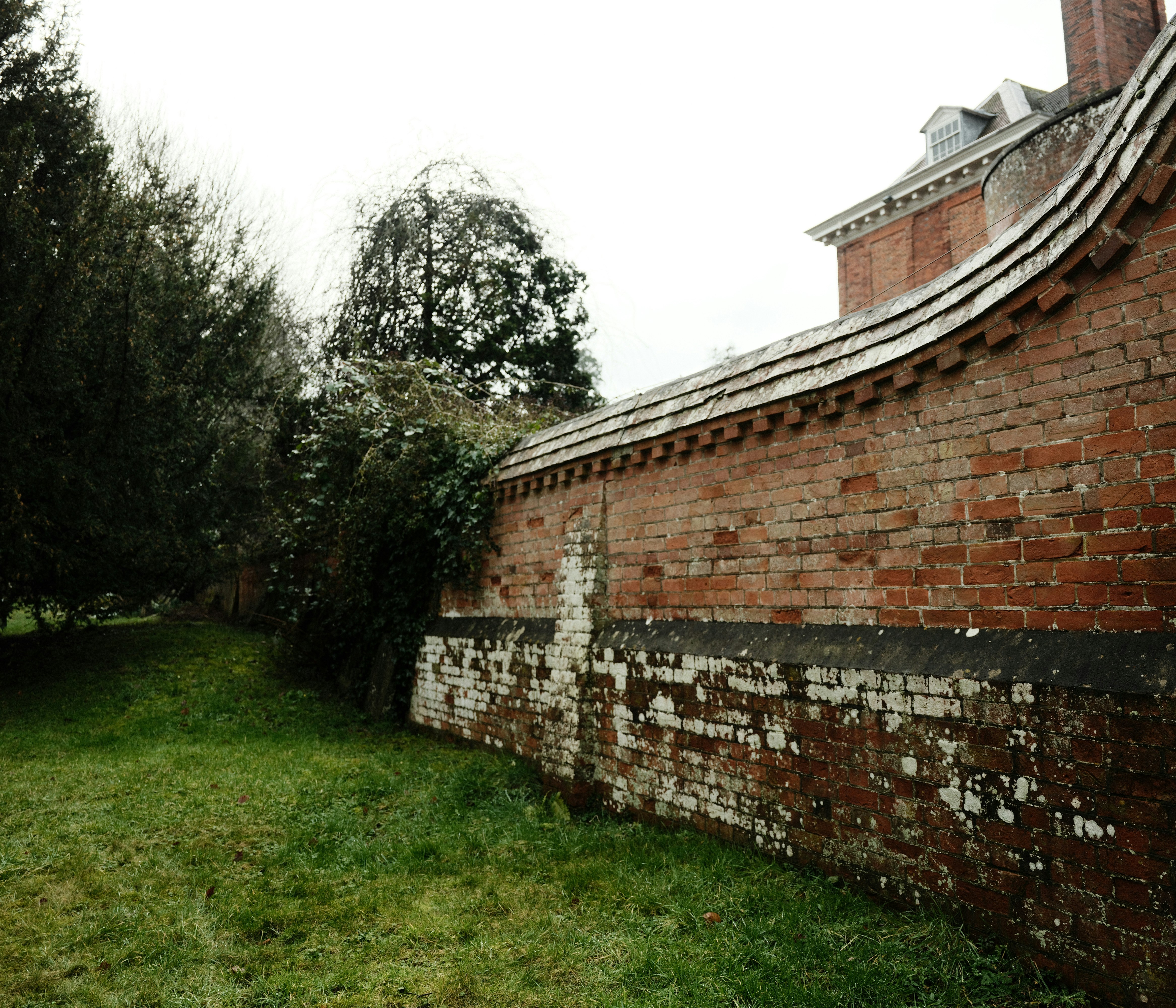 Um muro de tijolos desgastado curva ao redor de um gramado.
