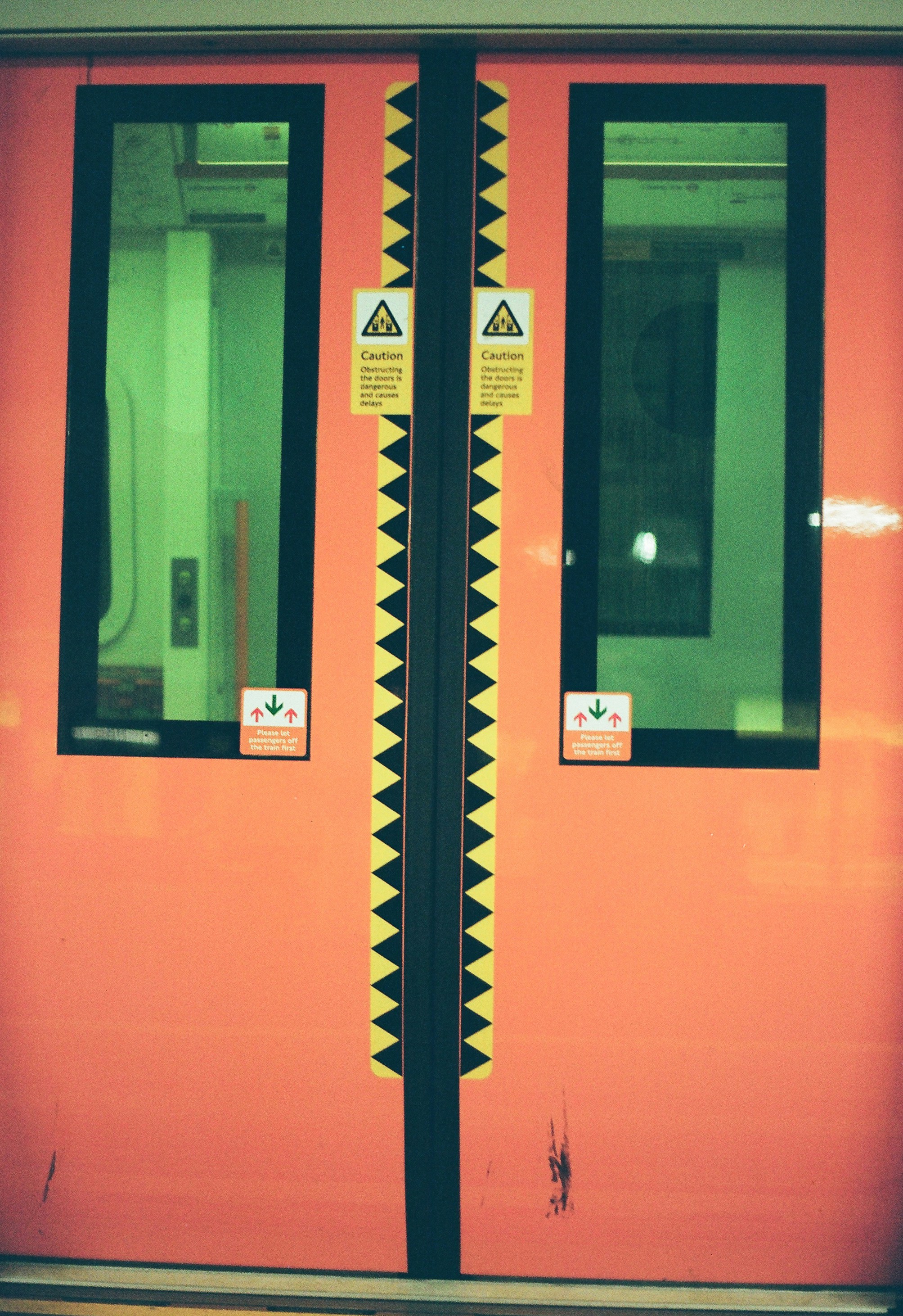 Orangefarbene Zugtüren mit Warnschildern und Fenstern