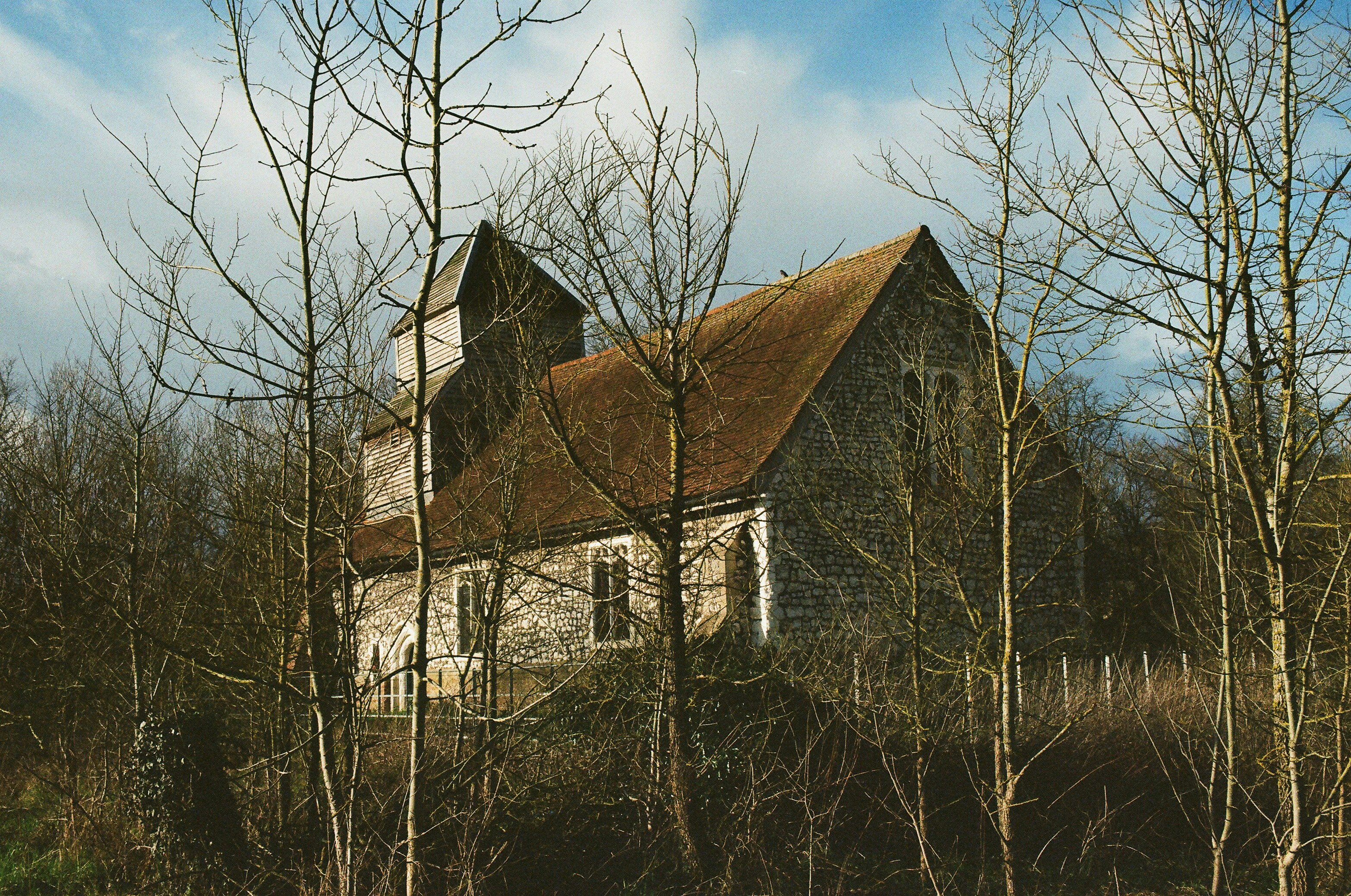 Old stone church partially hidden by bare trees