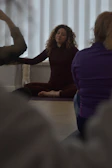 A woman leads a yoga class in a studio.