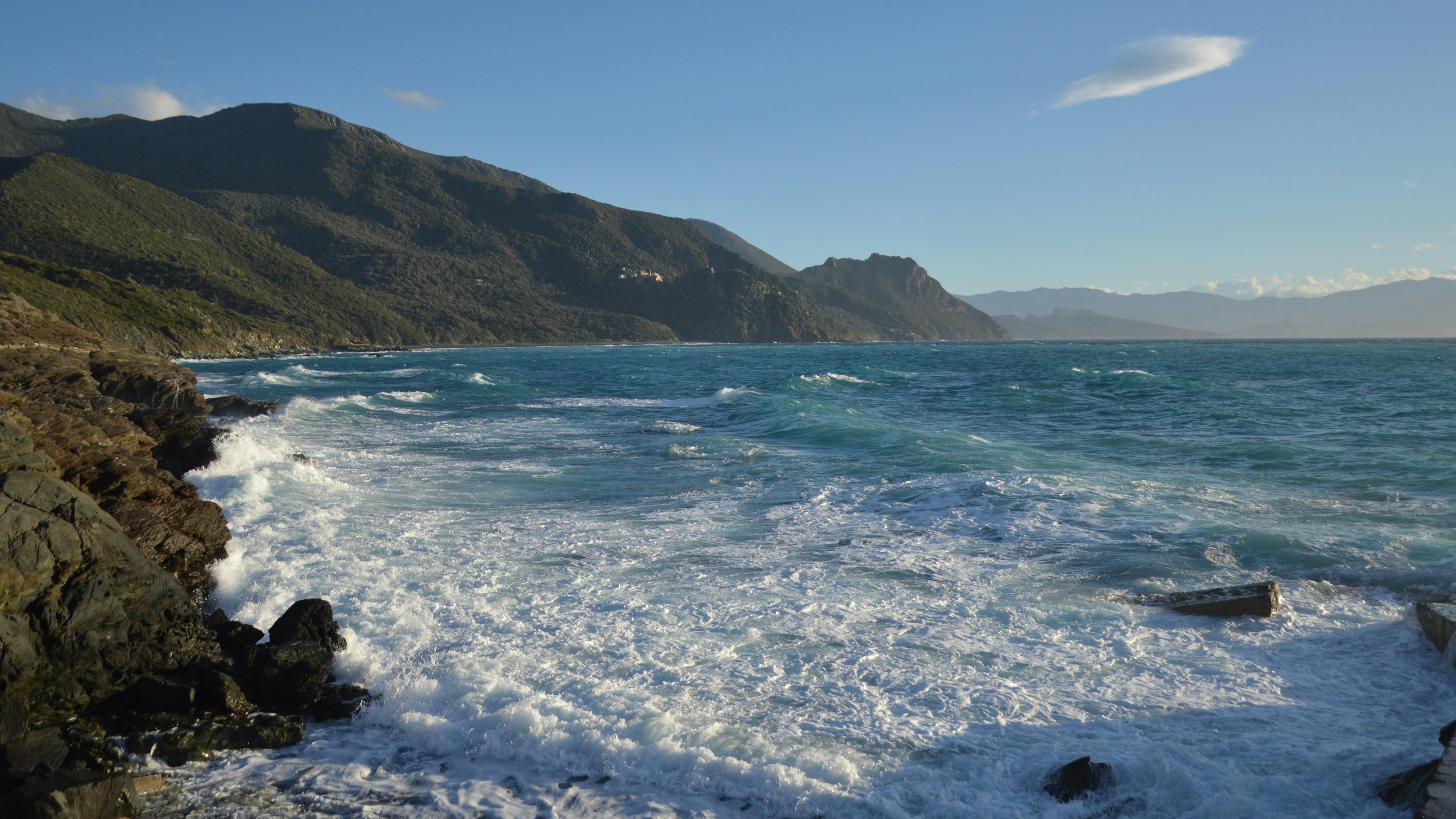 Waves crashing on a rocky coastline under a clear sky