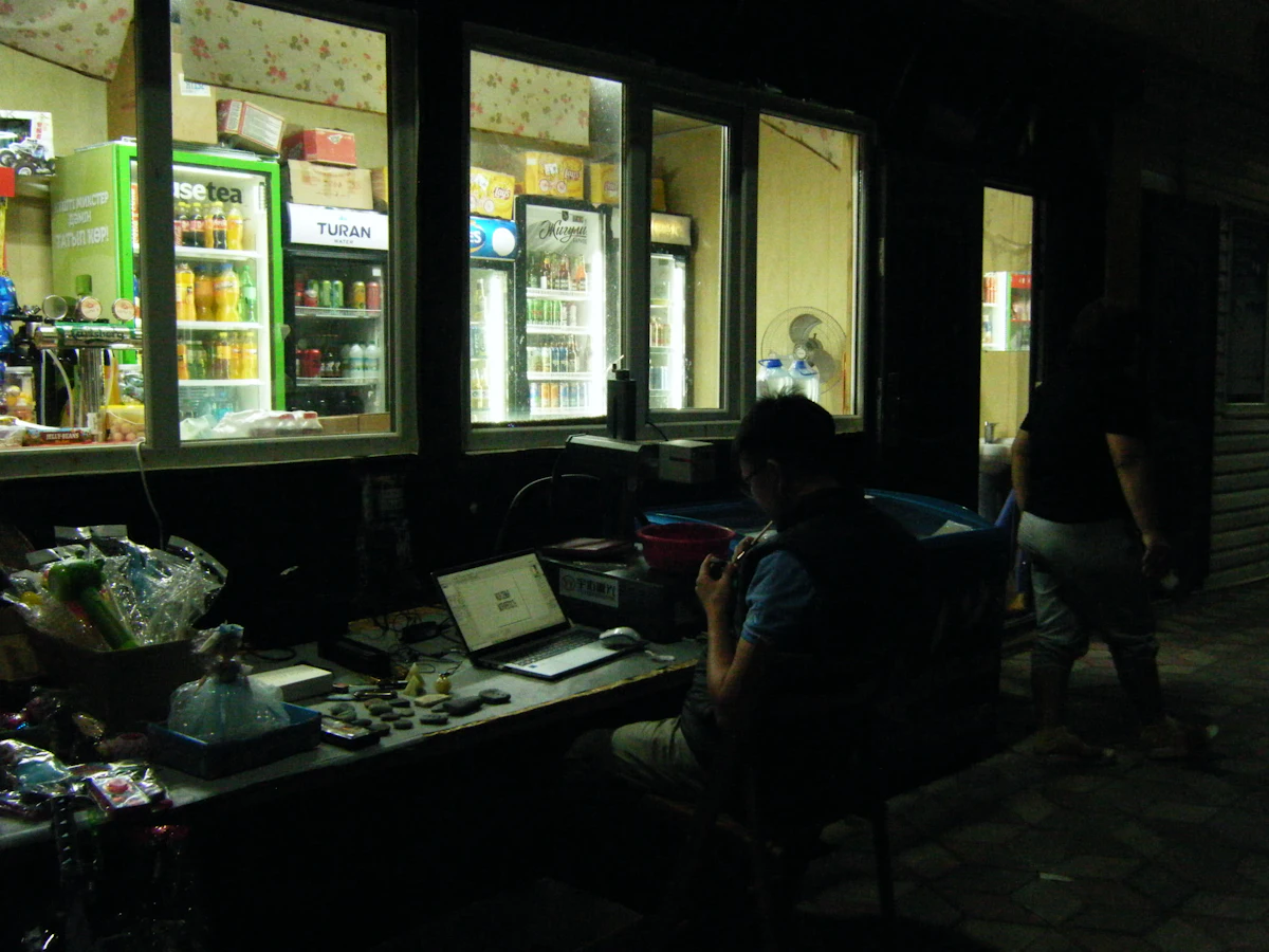 Pemilik toko bekerja dengan laptop dalam toko yang redup di malam hari