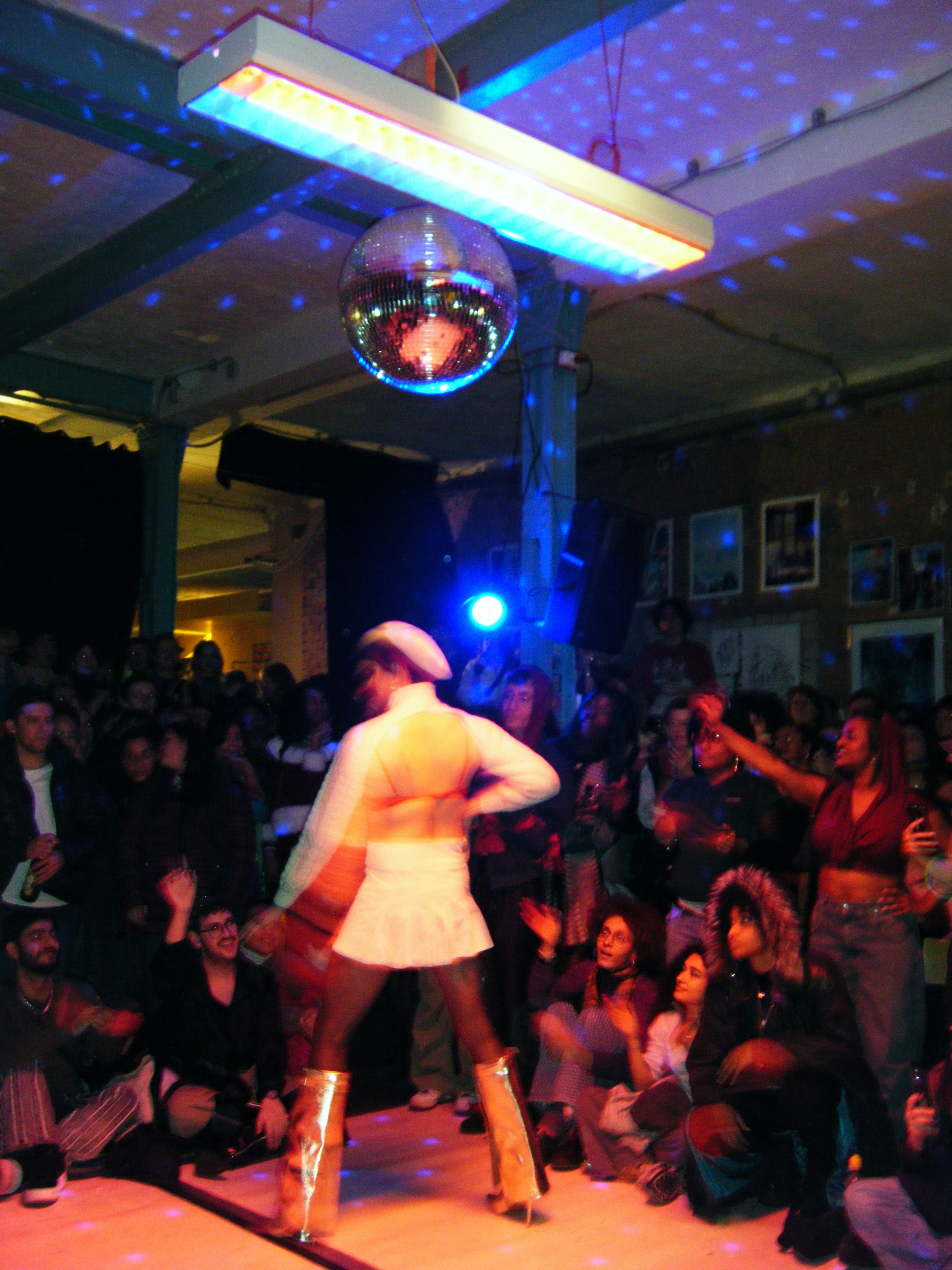 Woman dancing under disco ball in crowded room