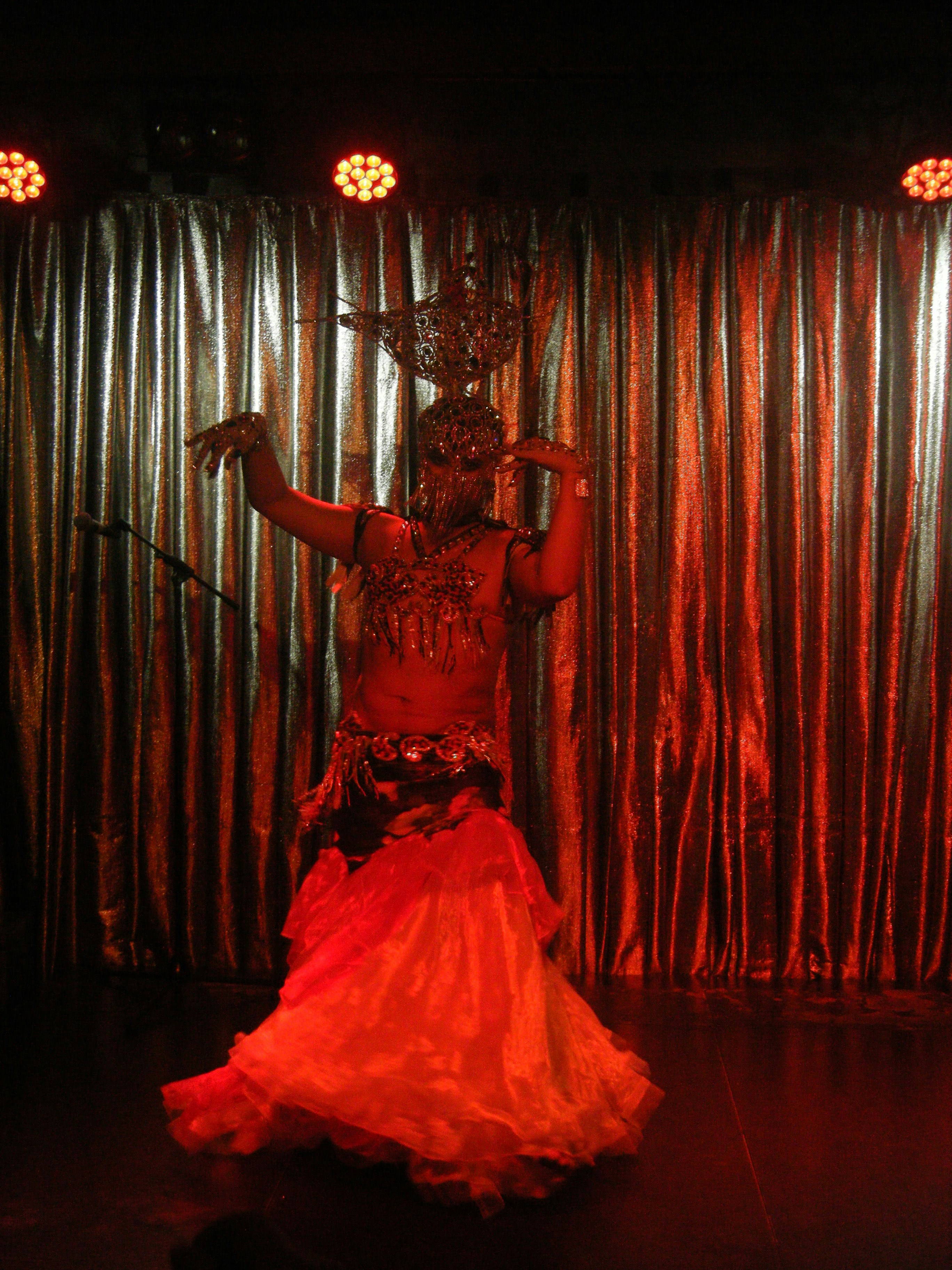 A performer balances a headdress while dancing on stage.