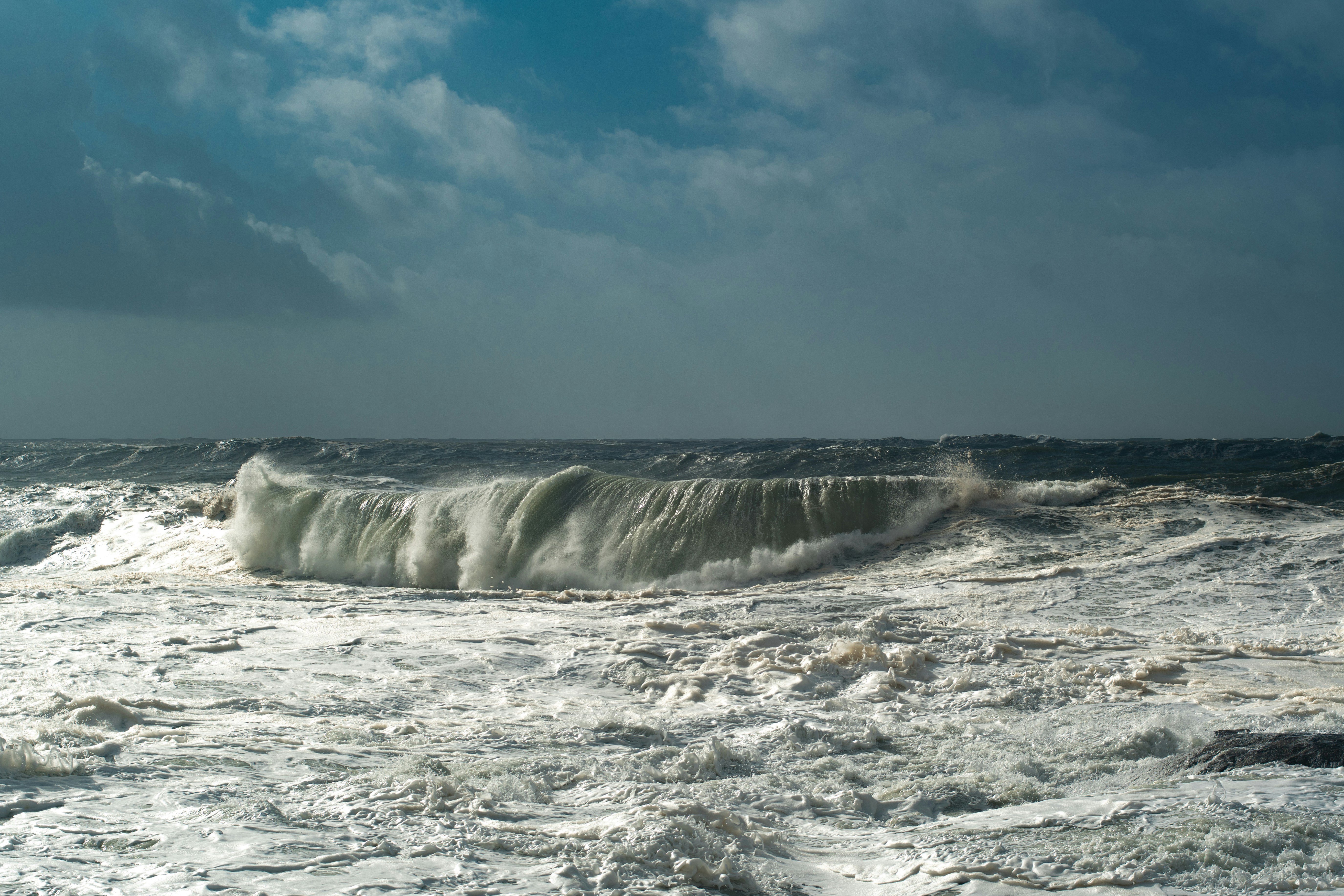 A large wave crashes in a stormy sea