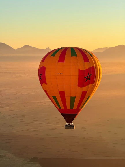 Hot air balloon floats over desert landscape at sunrise