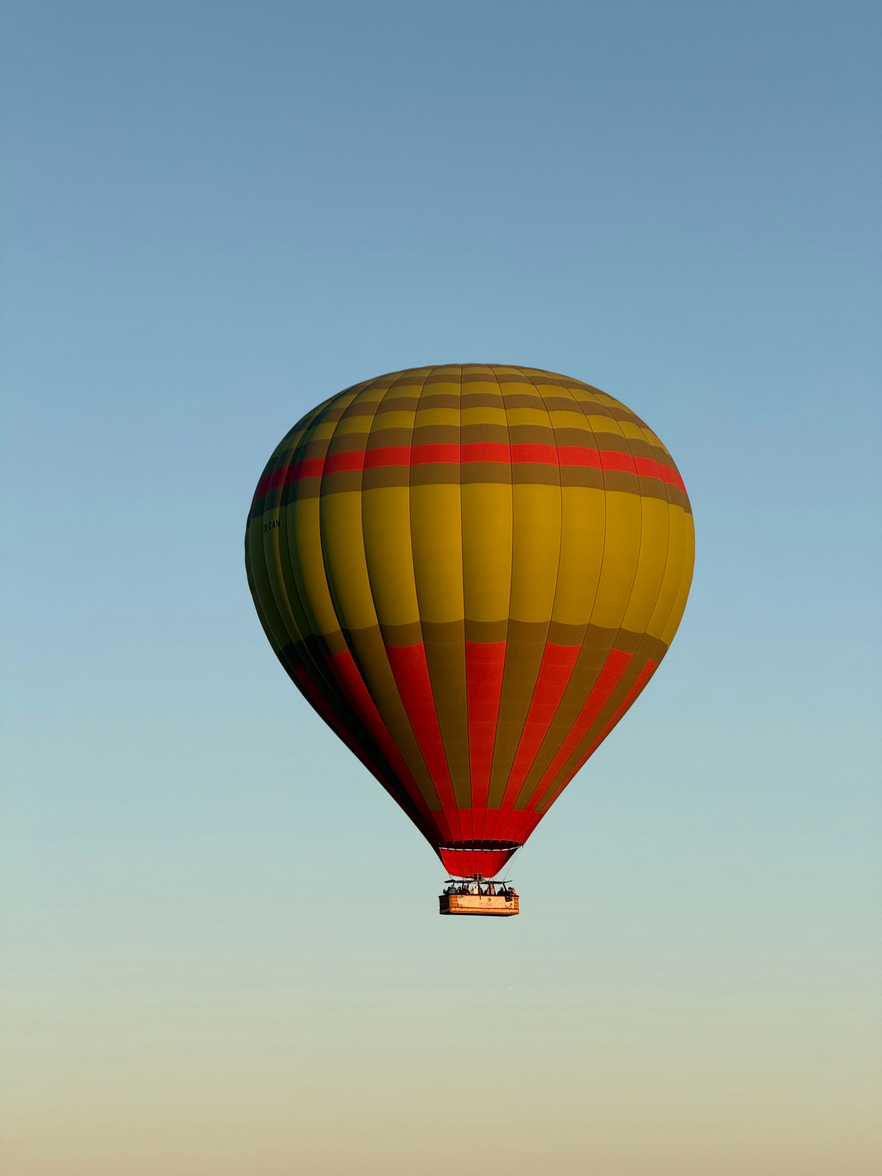 A hot air balloon floats against a clear blue sky.