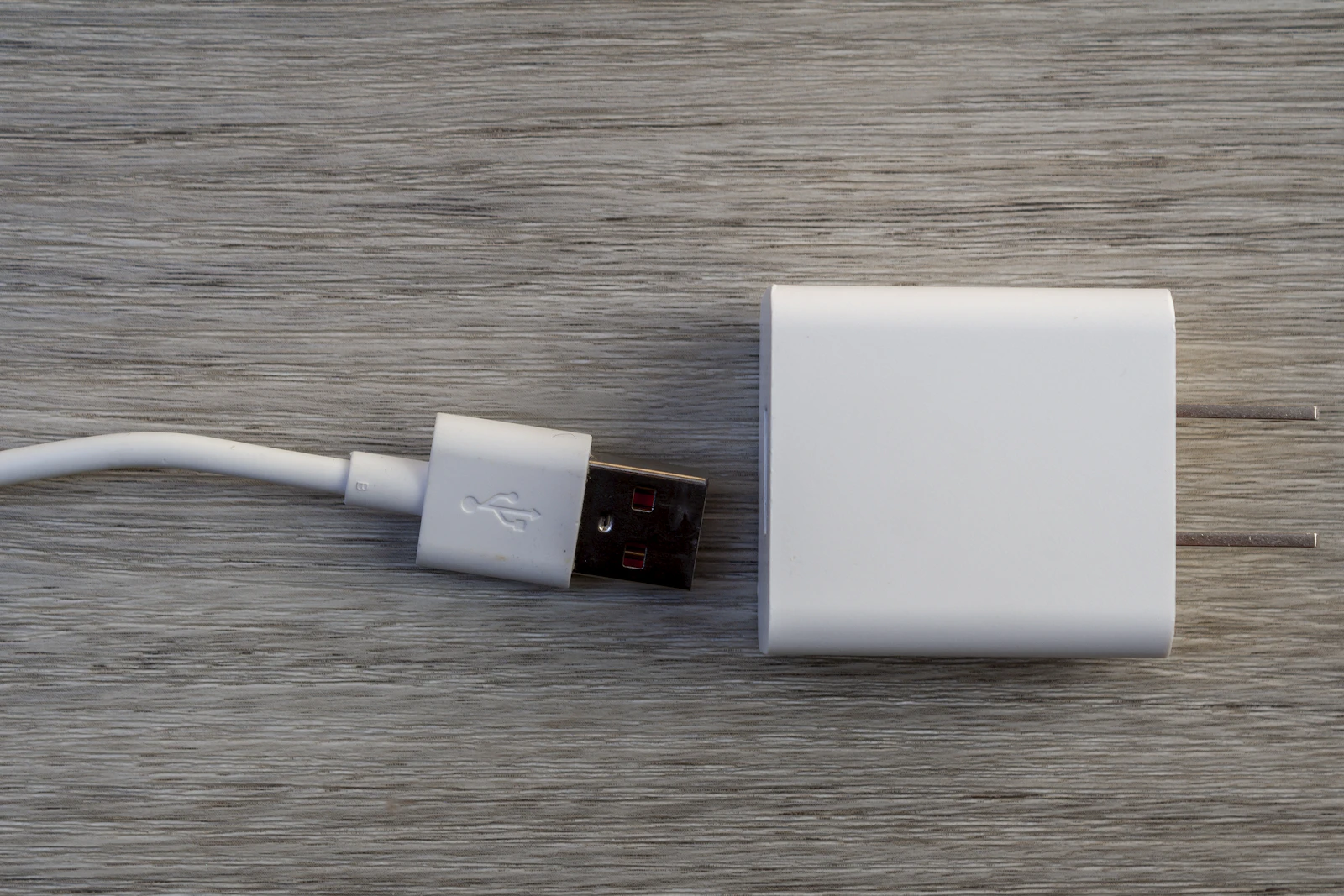 White USB wall charger and cable on a wooden desk