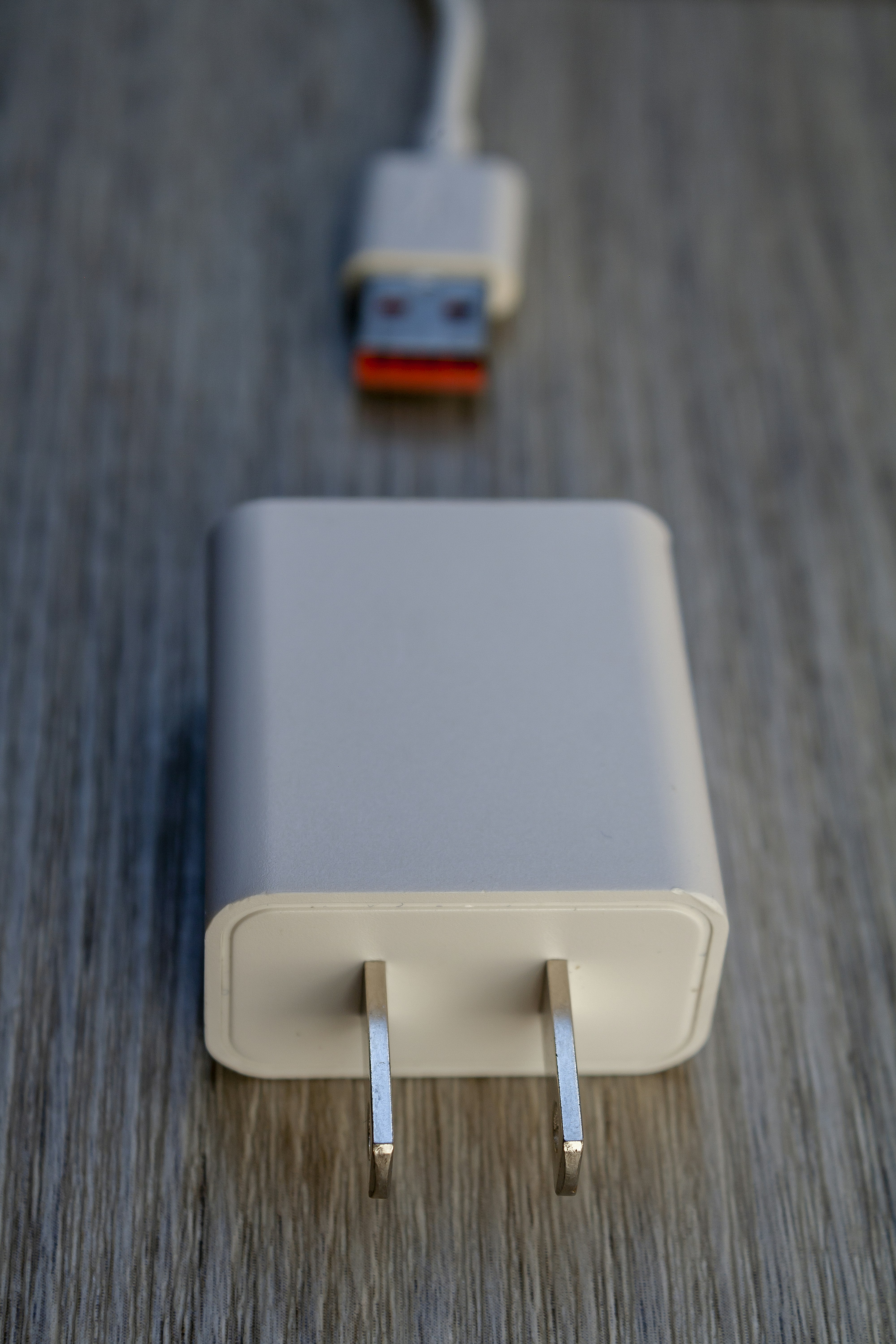 White power adapter and usb cable on wooden surface