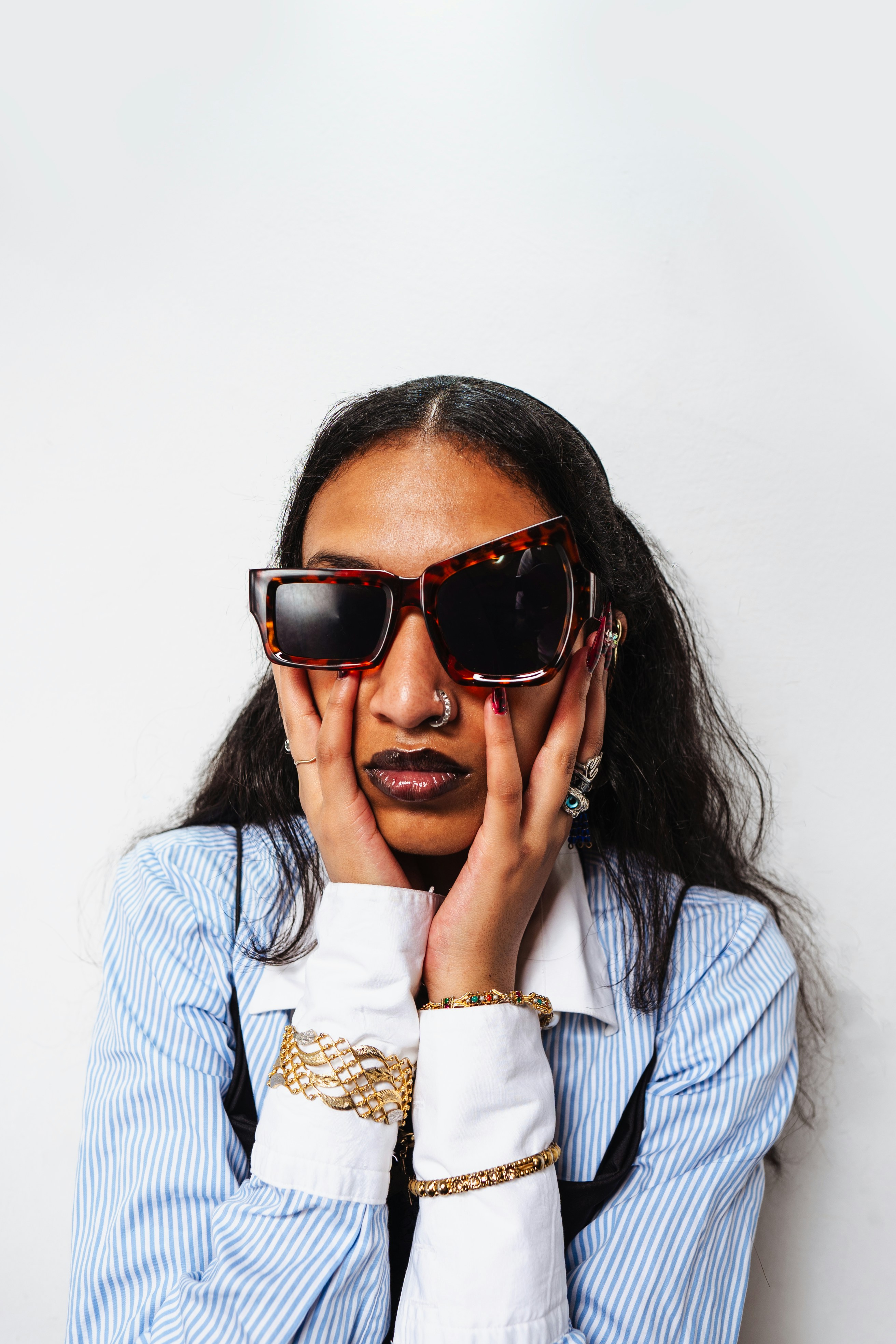 Woman with large sunglasses and jewelry touching her face