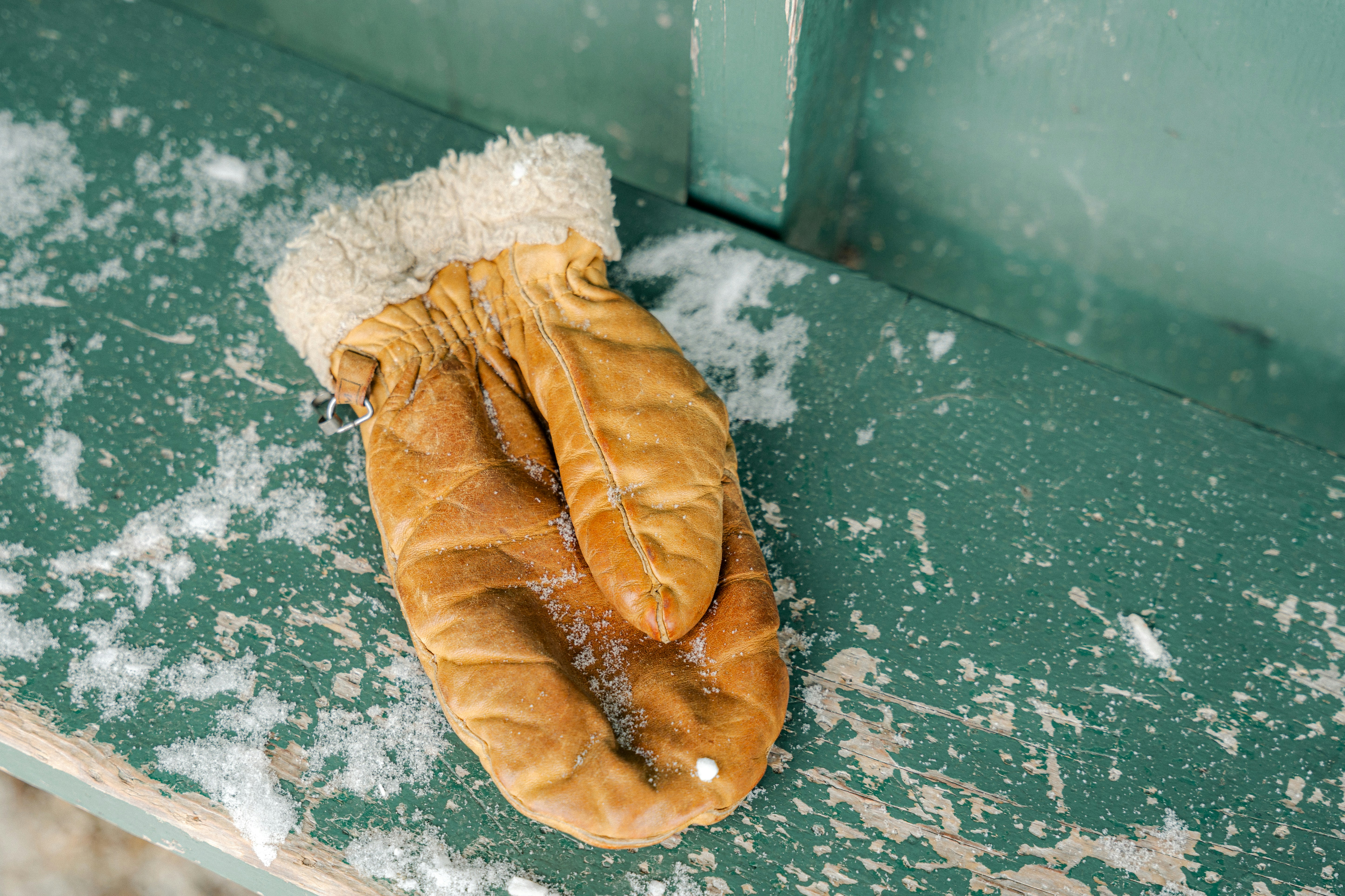 A single brown mitten lies in the snow.