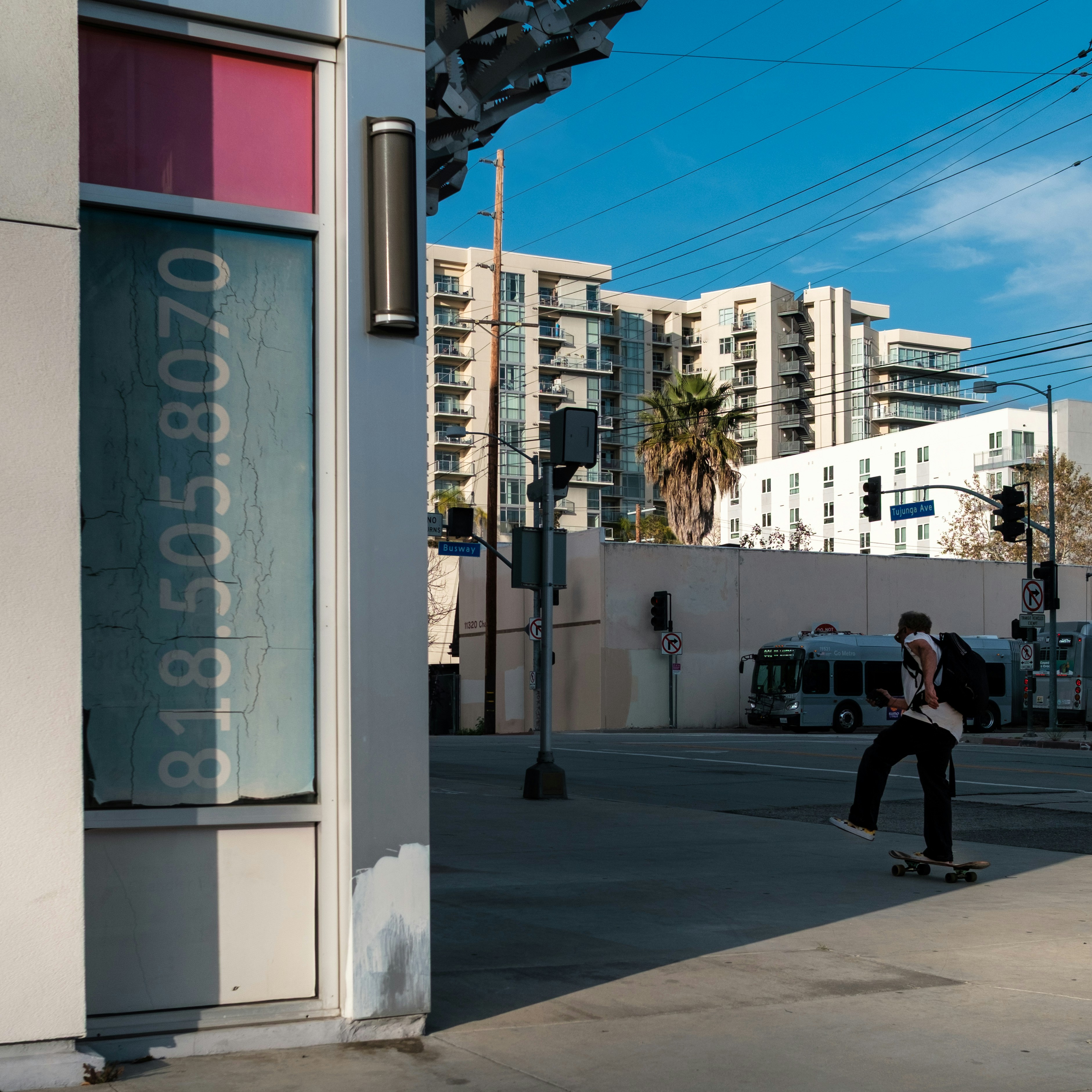A person skateboarding on a sunny urban street.