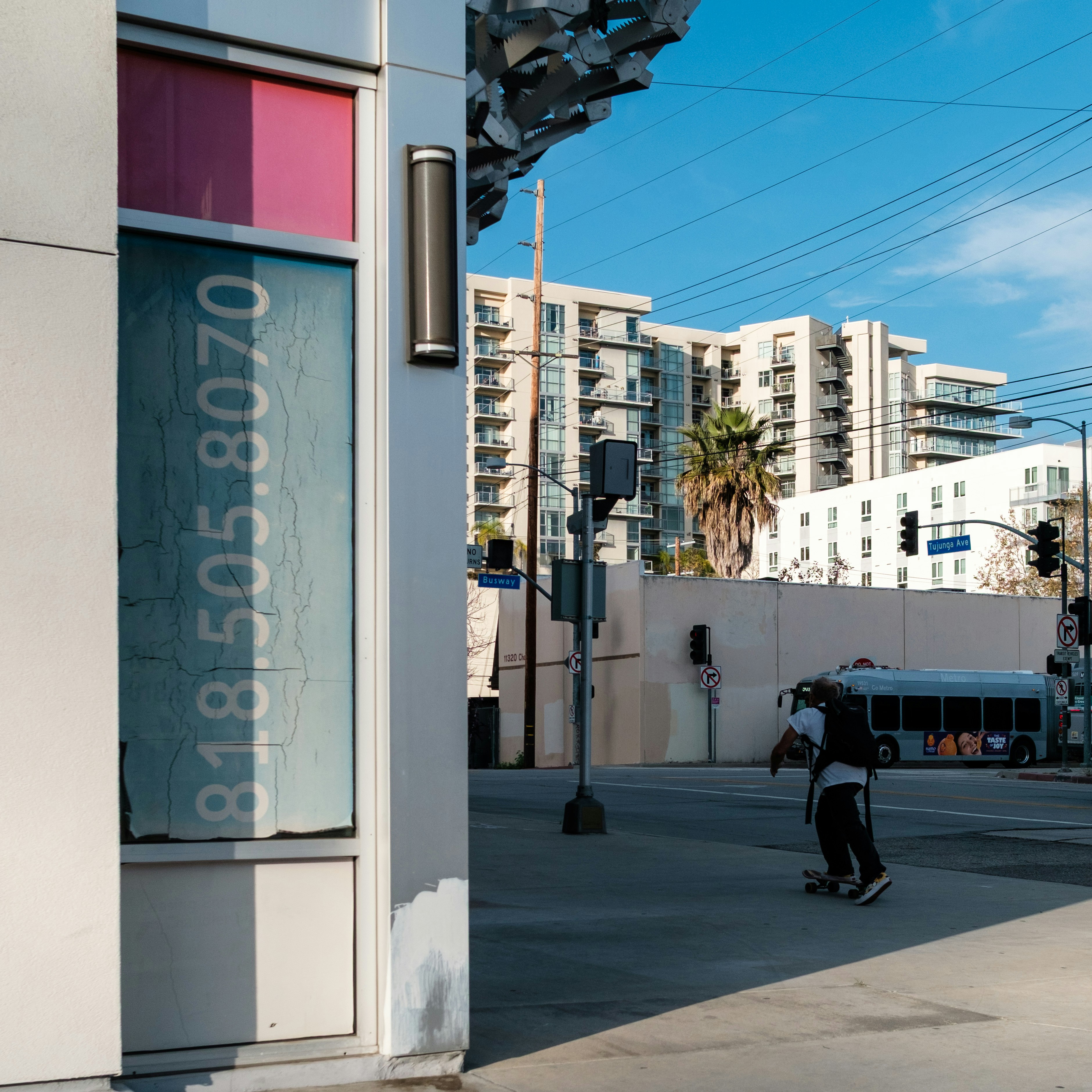 Skateboarder on a street with buildings and bus.