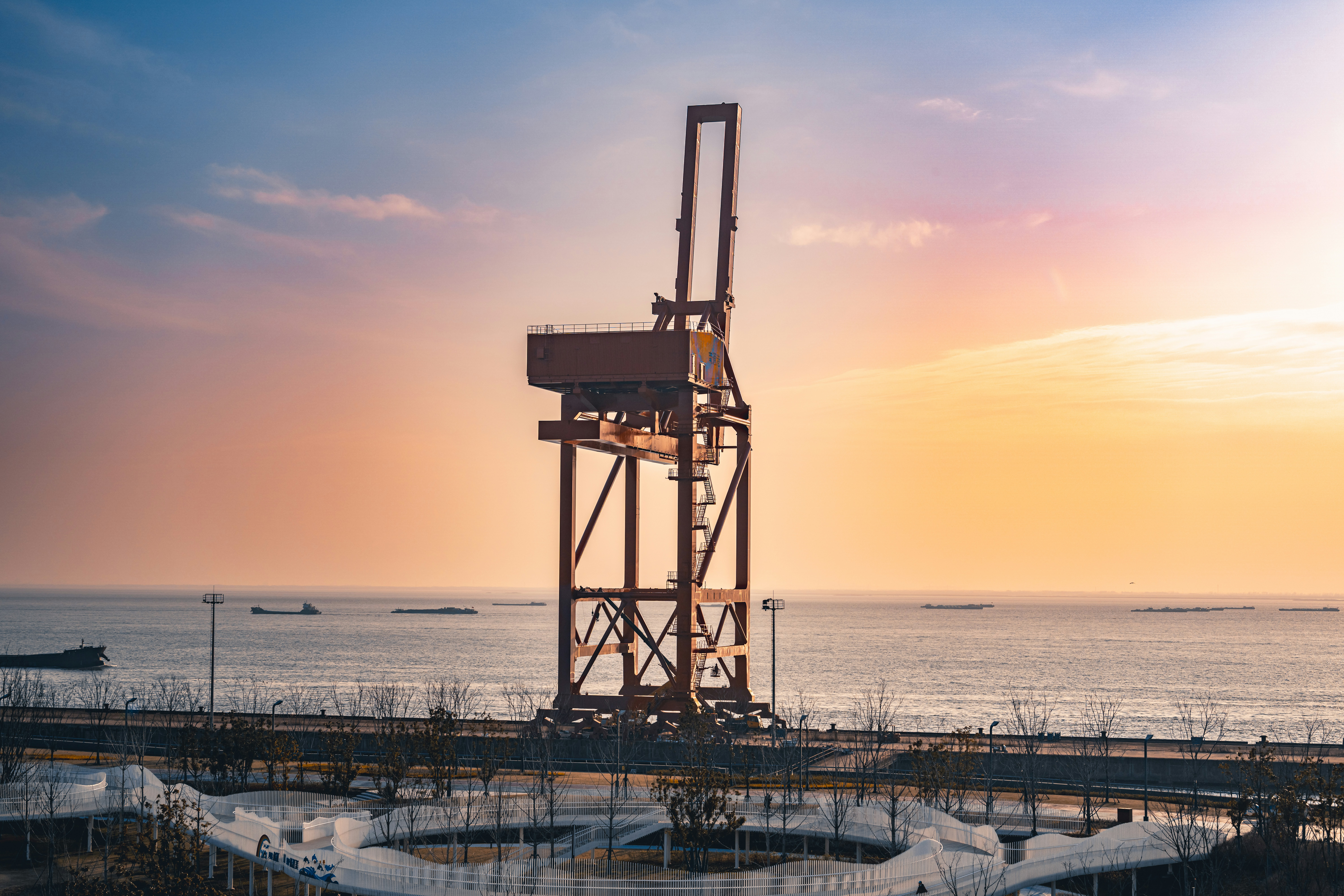 夕暮れ時に海辺に立つ大型産業用クレーン