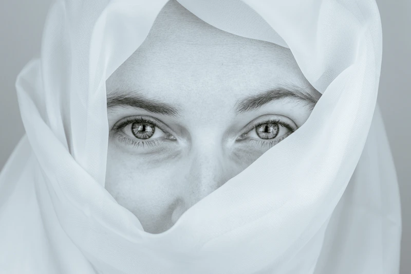 Beyaz kumaş arasından bakan kadın gözleri