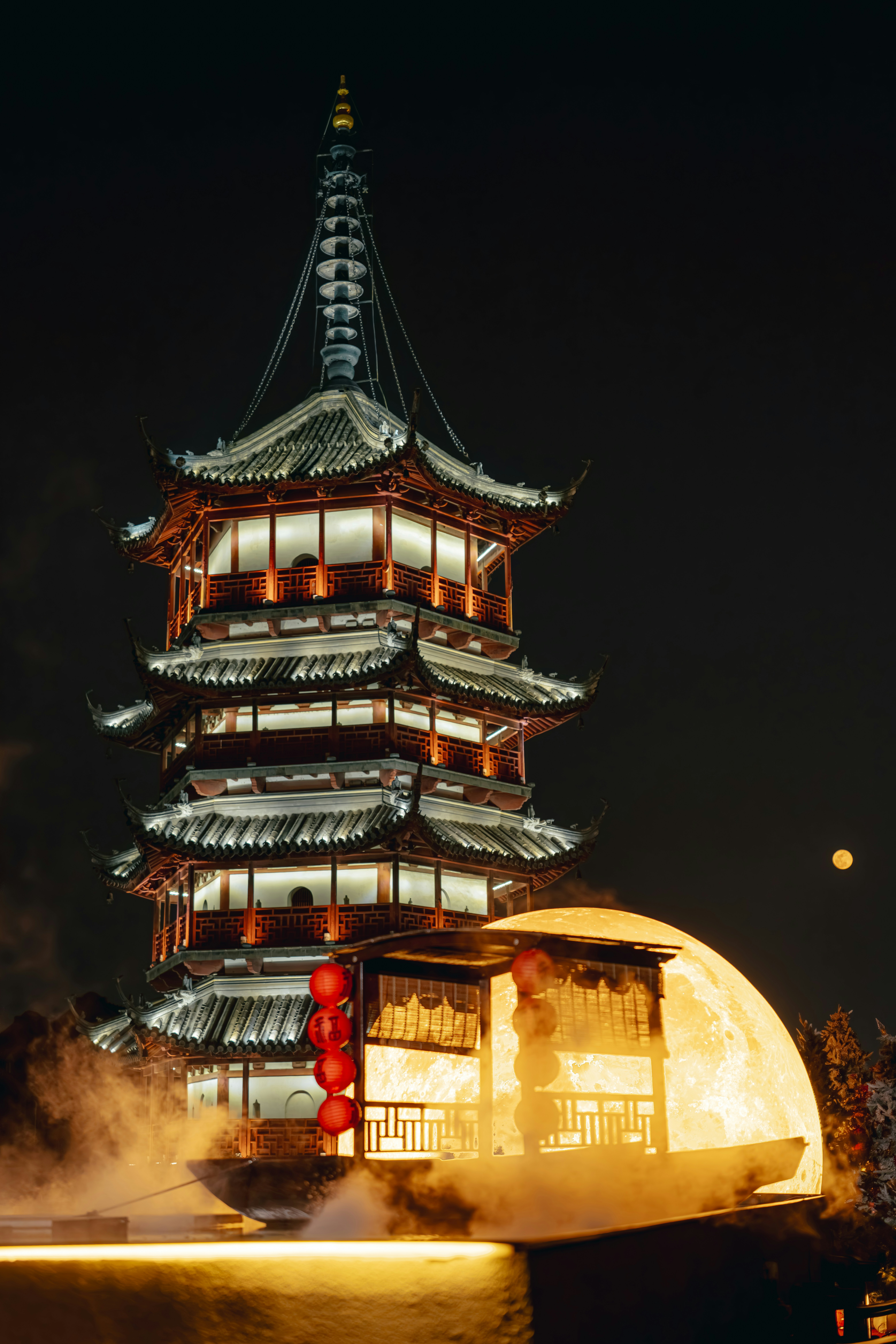 A traditional pagoda illuminated at night with a large moon