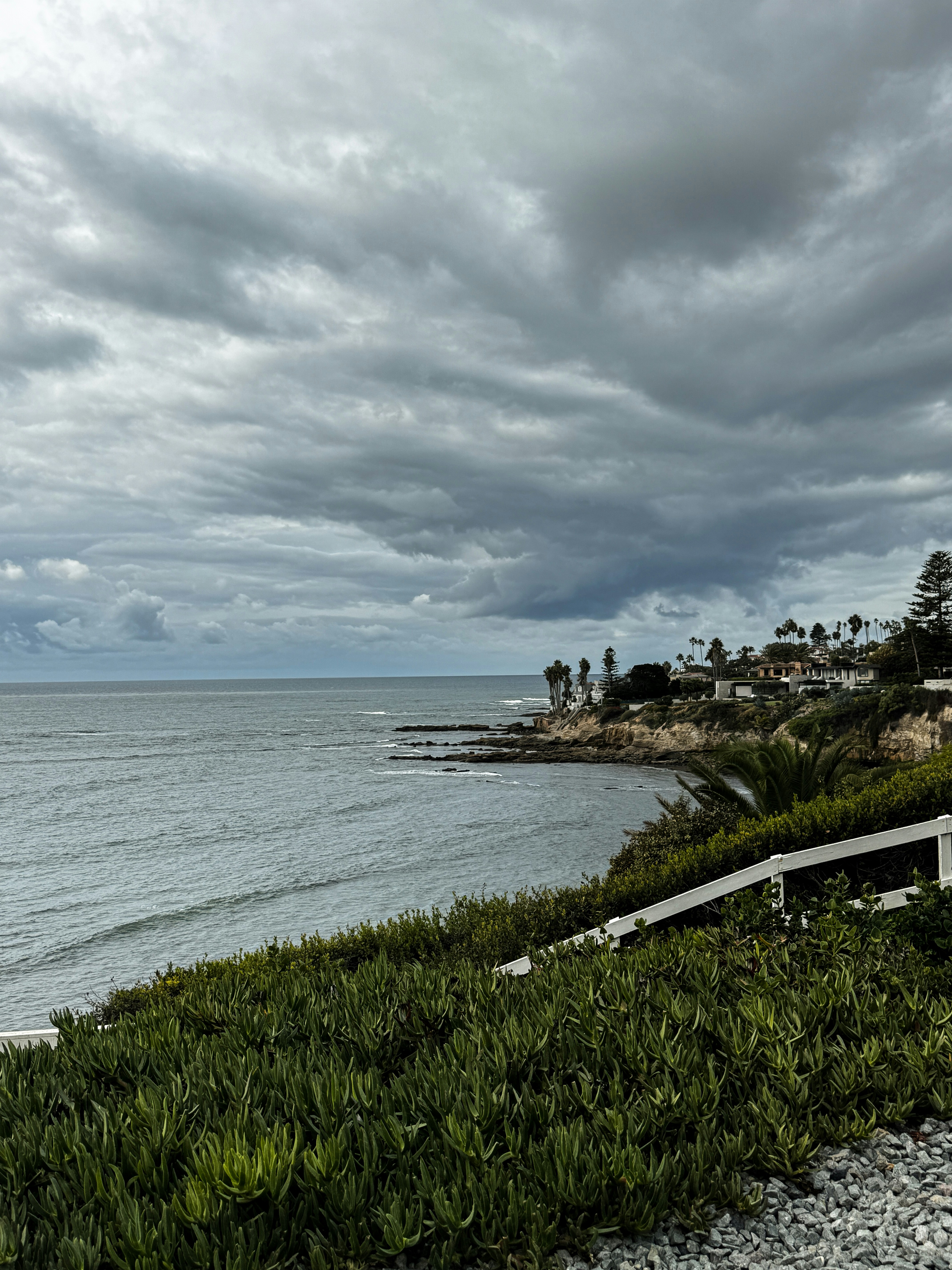 Overcast sky above a calm ocean and coastal homes.