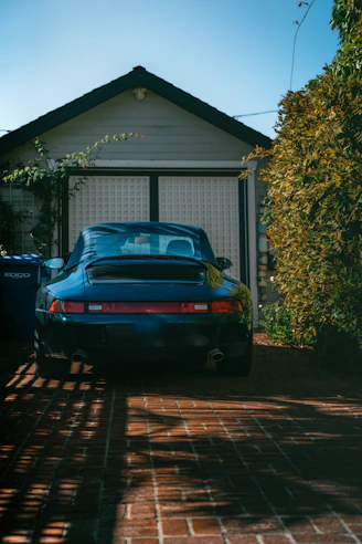 Dark blue sports car parked in front of garage