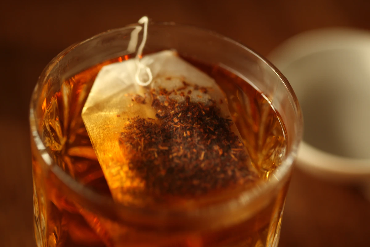 A glass of warm tea with a tea bag steeping in sunlight