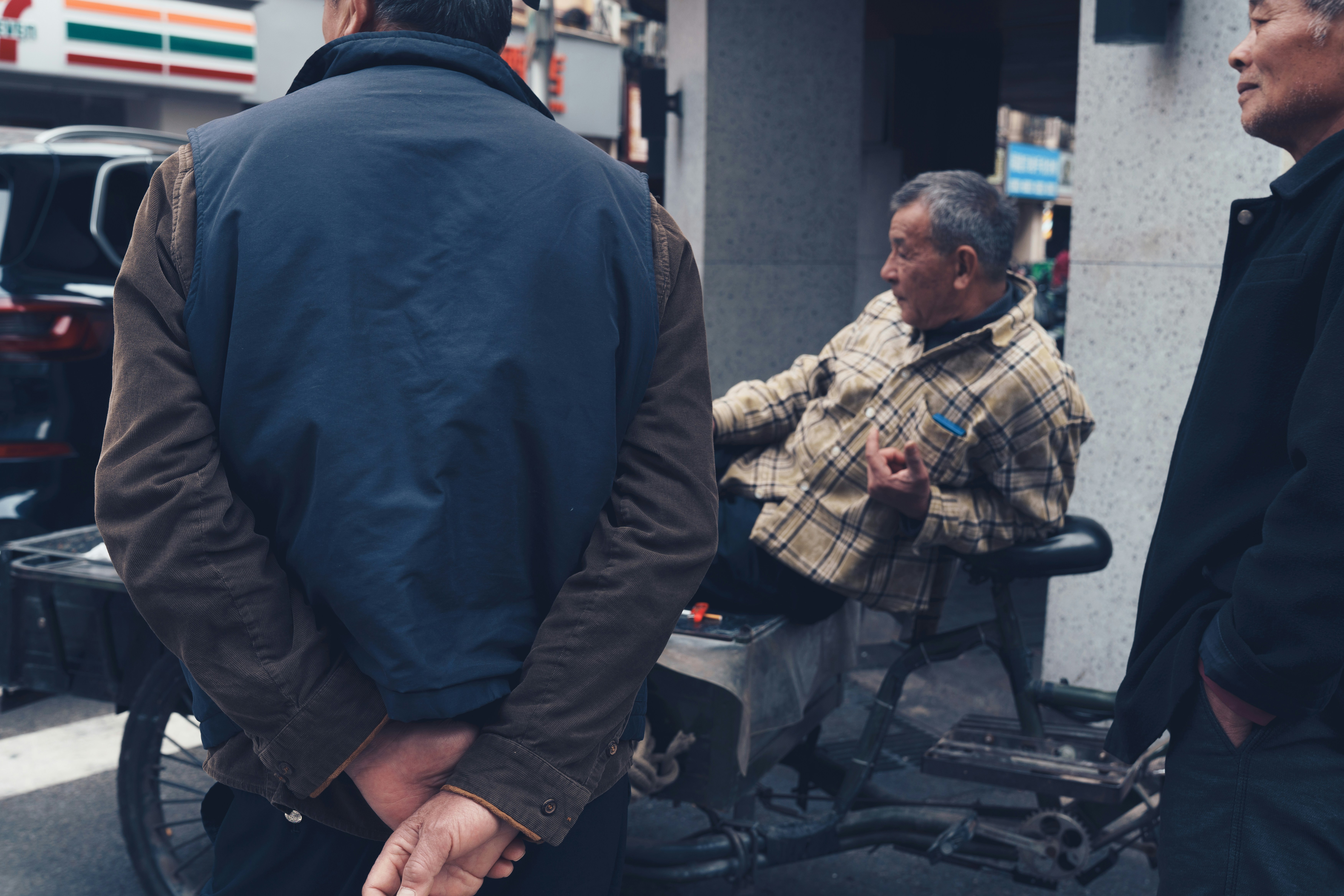 Three men interacting on a city street.