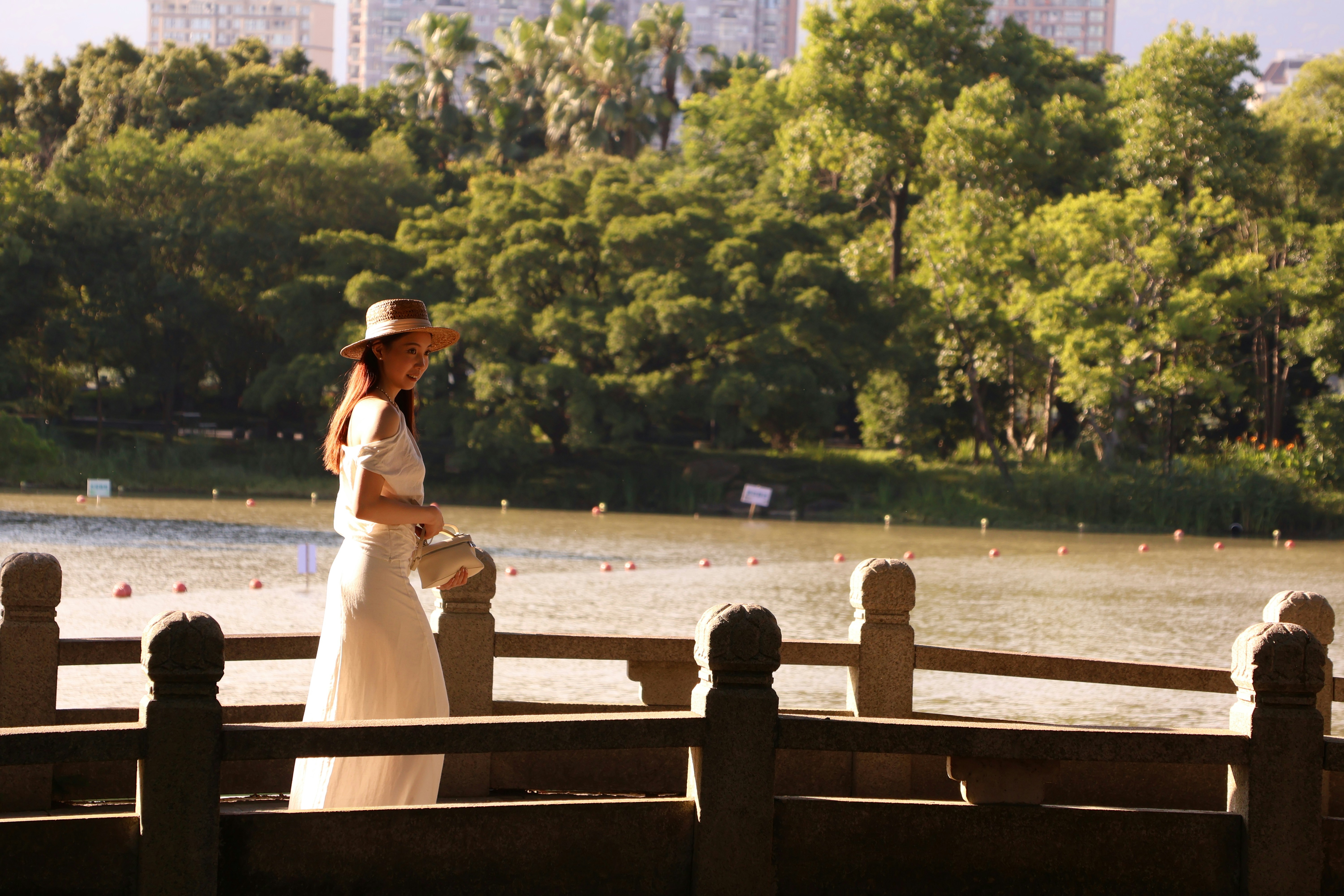 Woman in a white dress walking by a lake