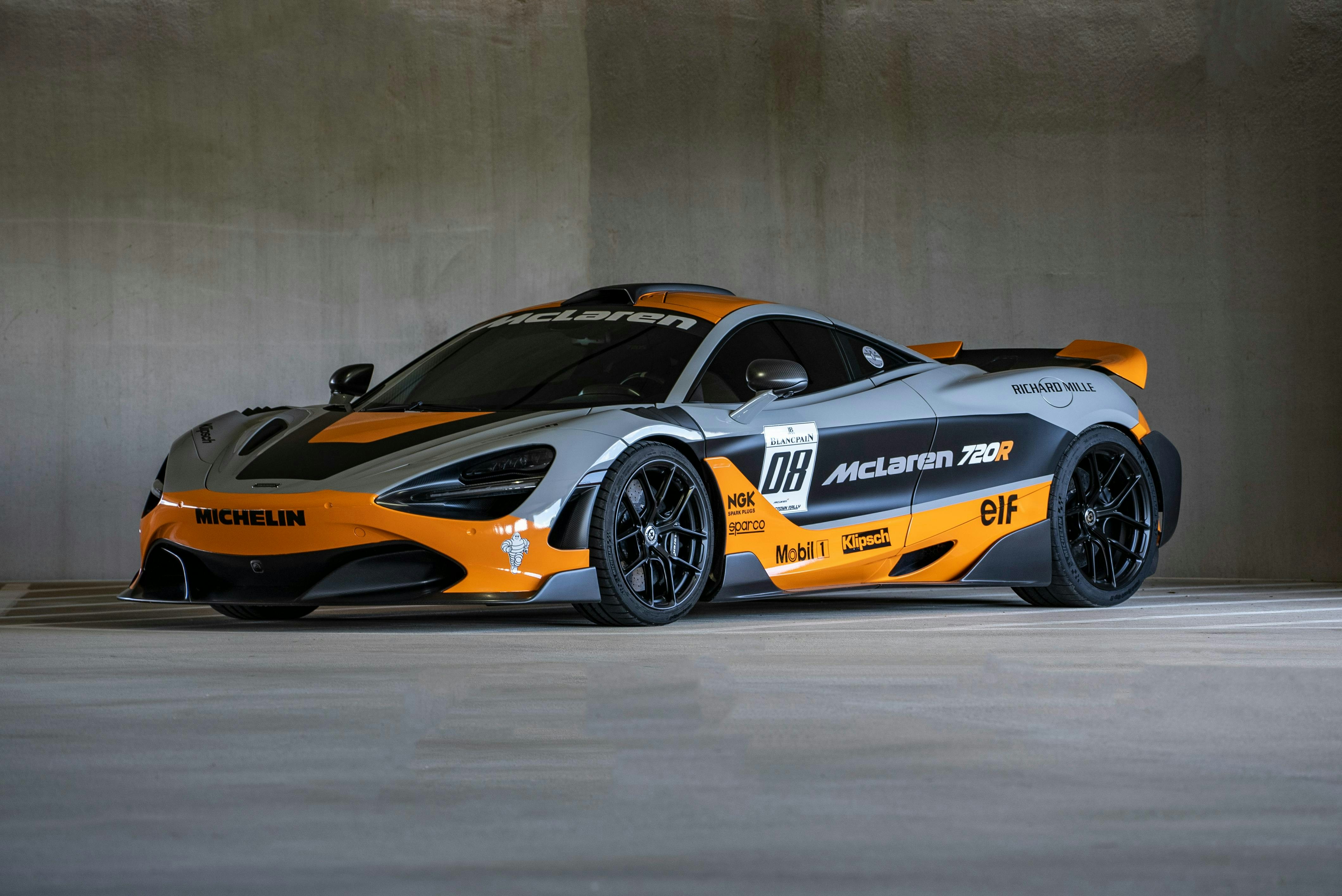 A grey and orange mclaren race car parked indoors