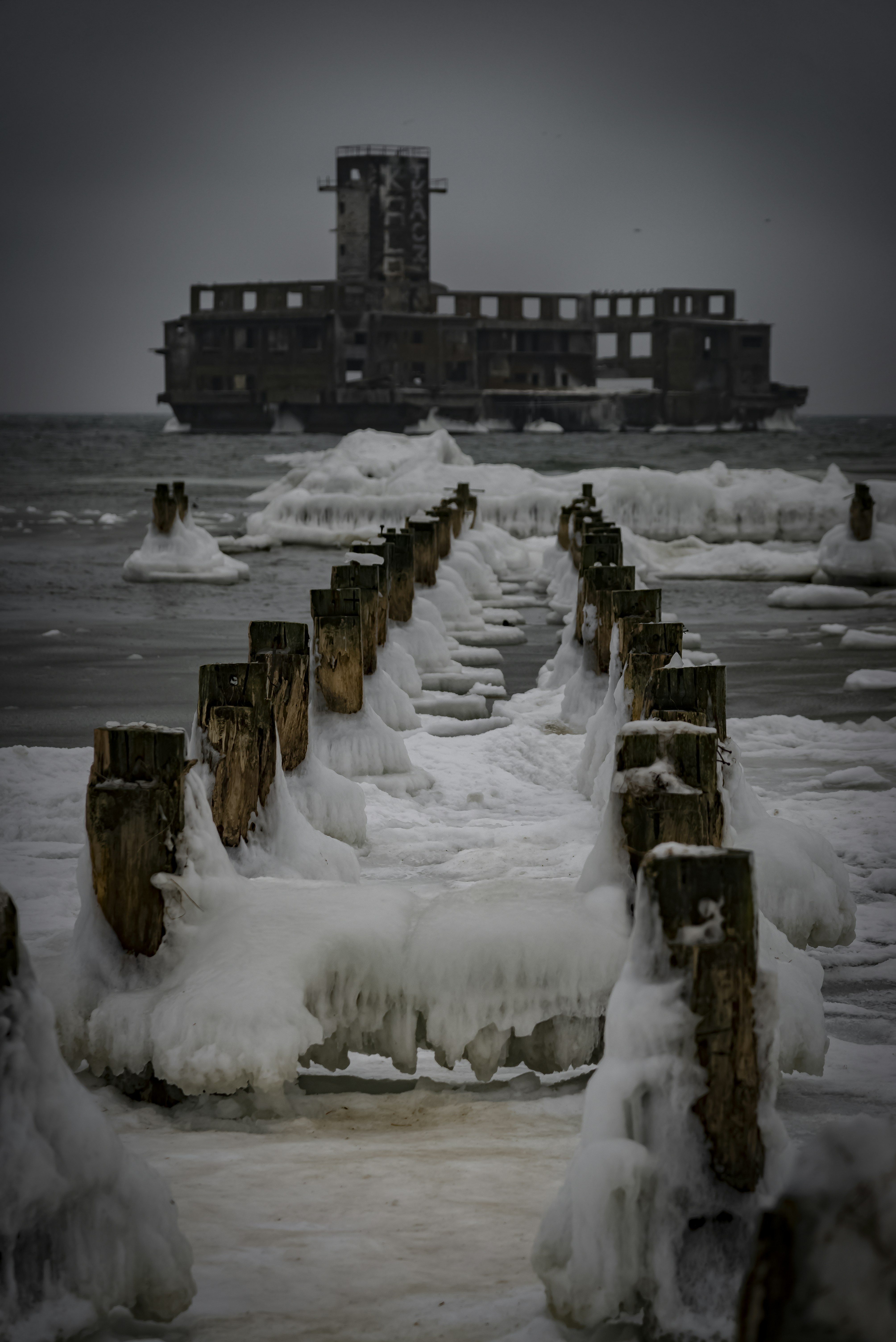 Frozen pier leading to a decaying building offshore
