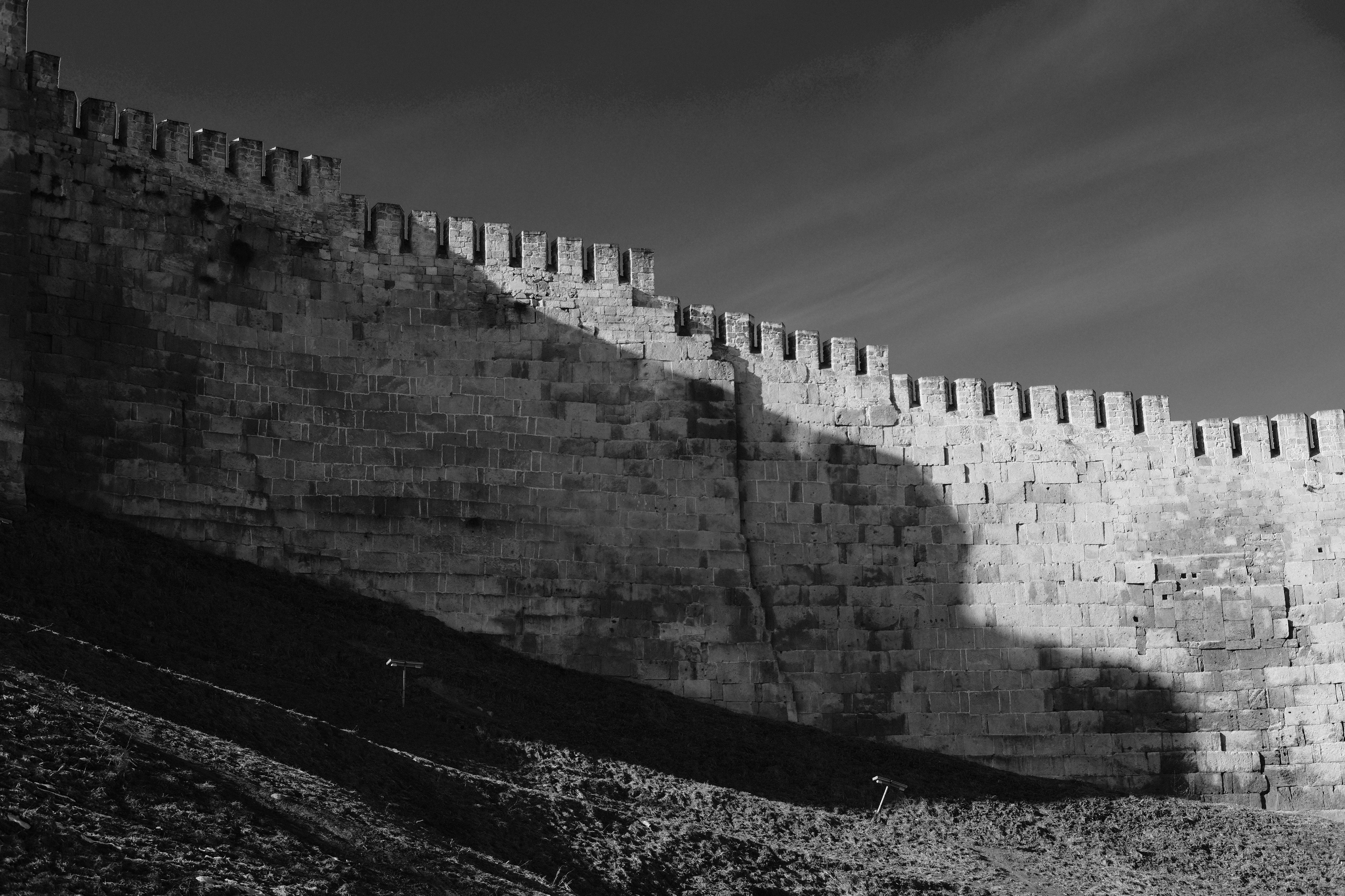 Ancient stone wall with crenellations and shadows.
