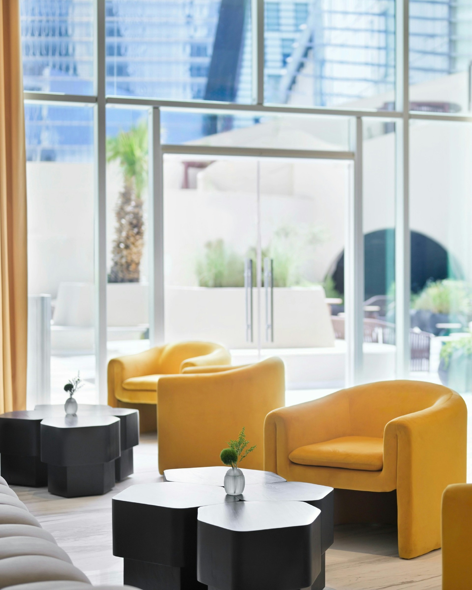 Modern lounge area with yellow chairs and geometric tables.