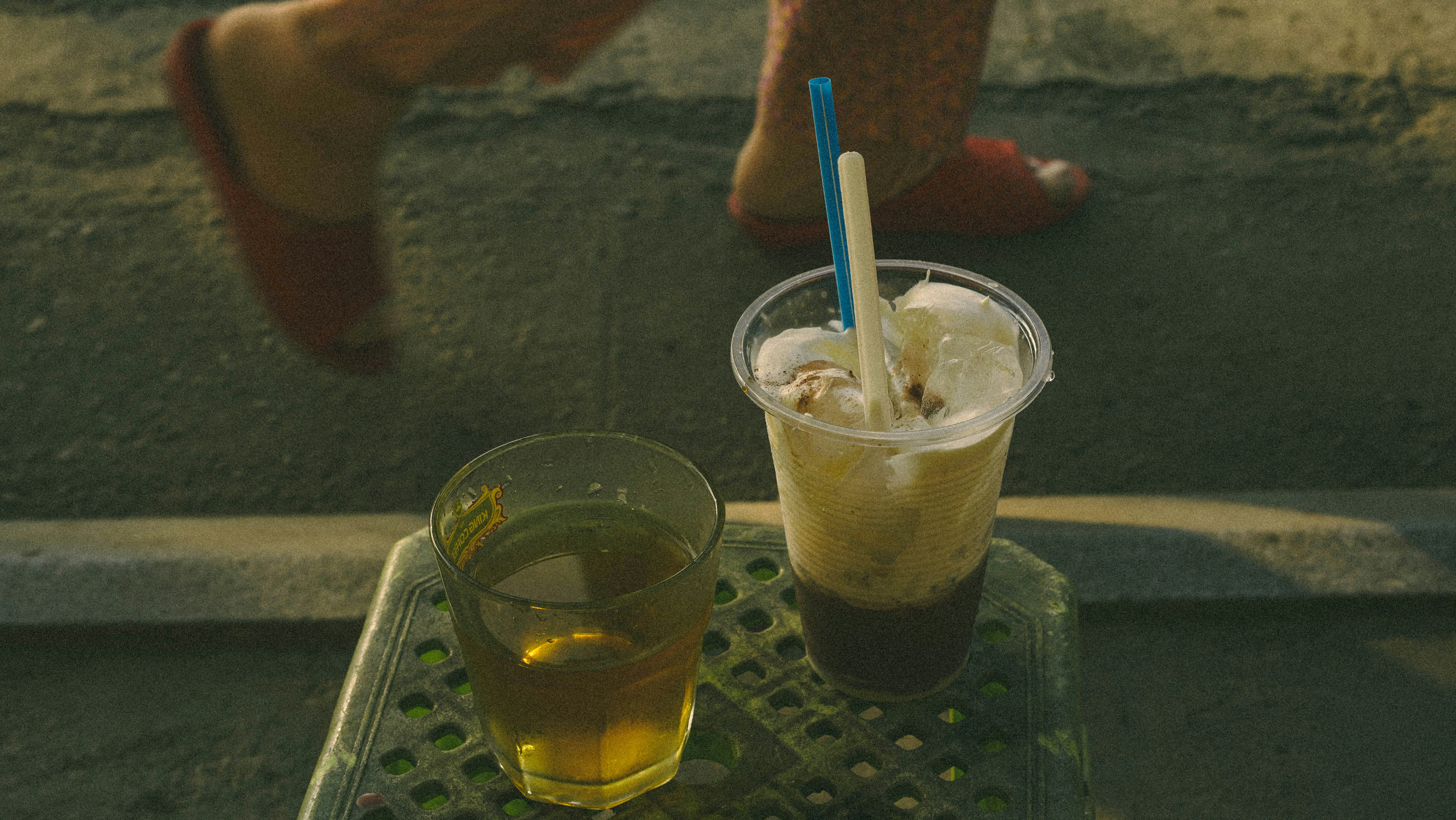 Duas bebidas e passos de uma pessoa passando.