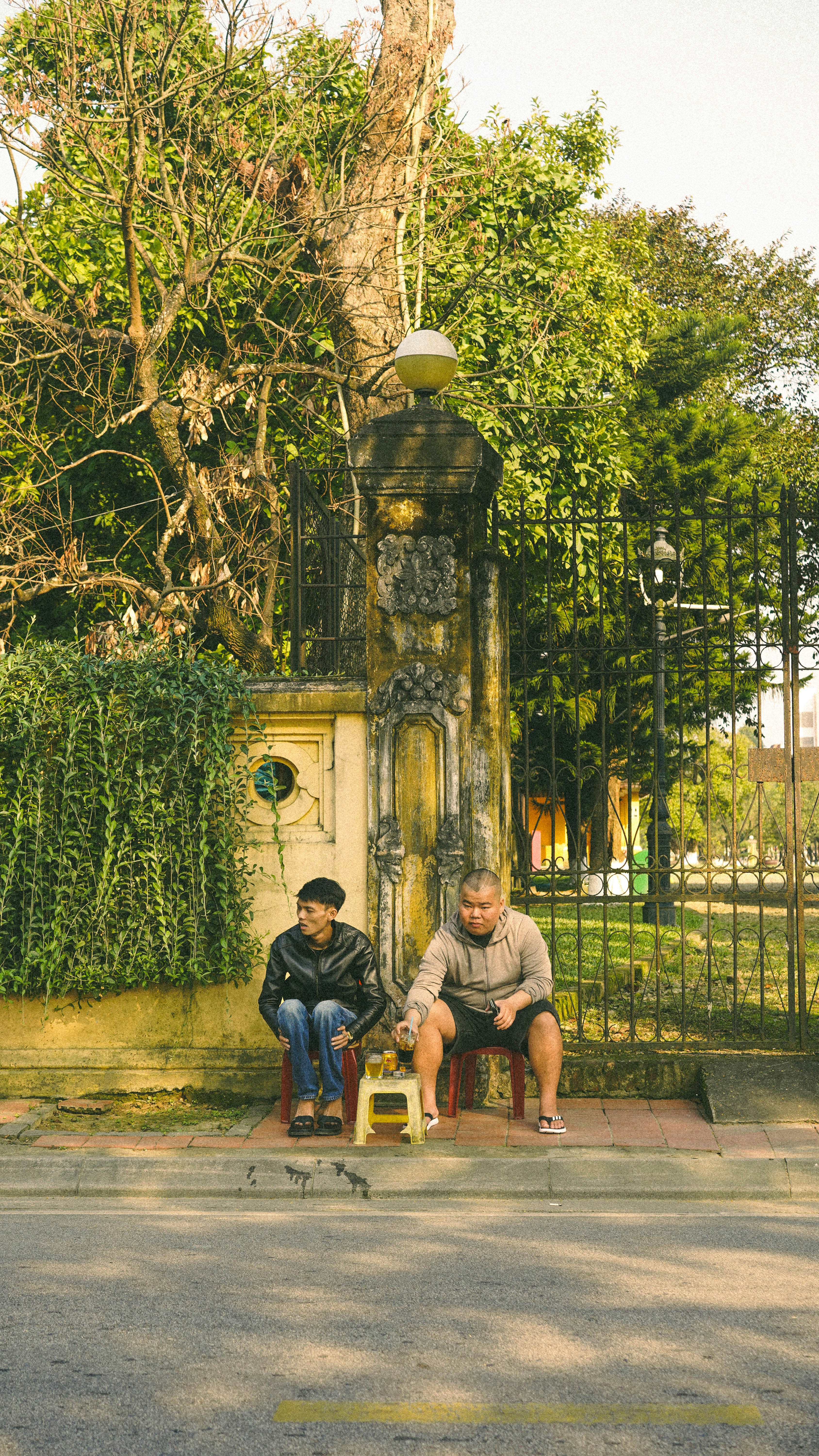 Two men sit on chairs next to a gate