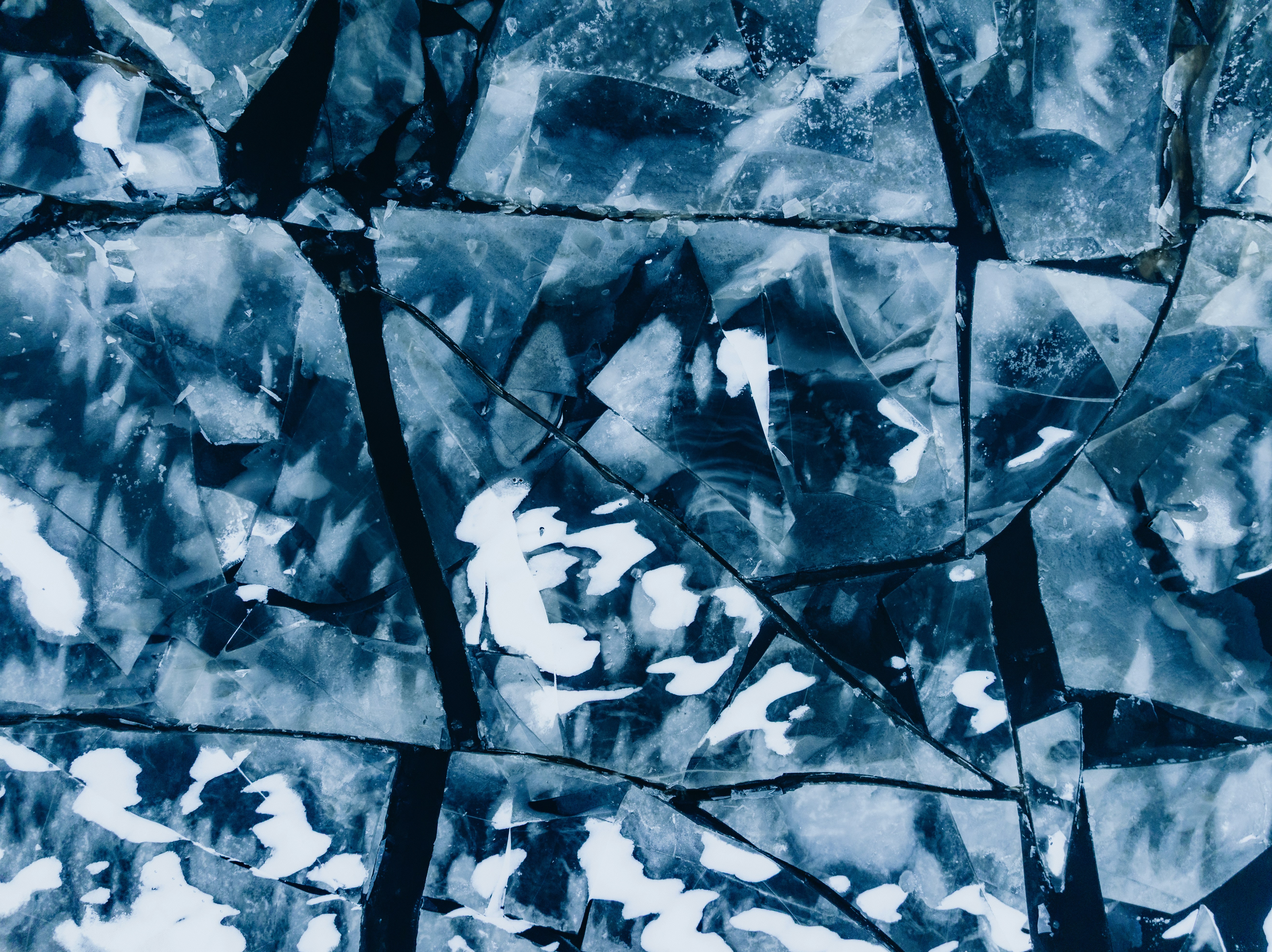 Cracked ice surface with white snow patches