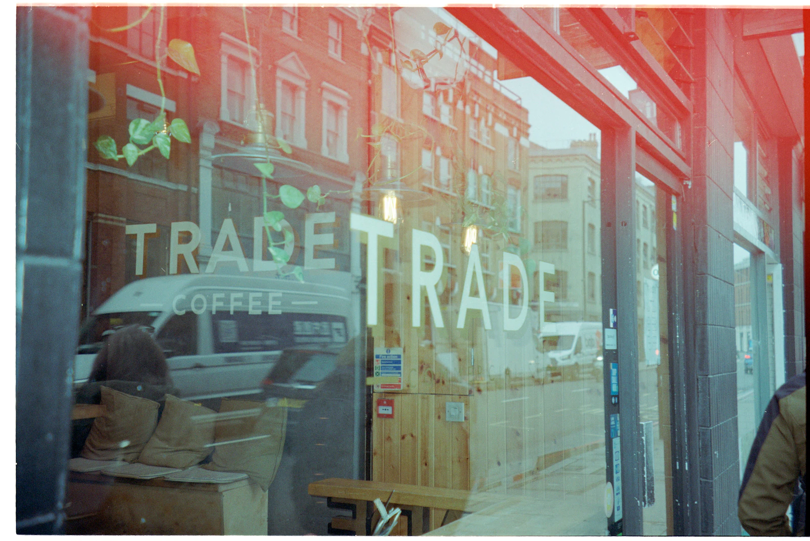 A city street and passing light are reflected across the window of a quiet coffee shop.