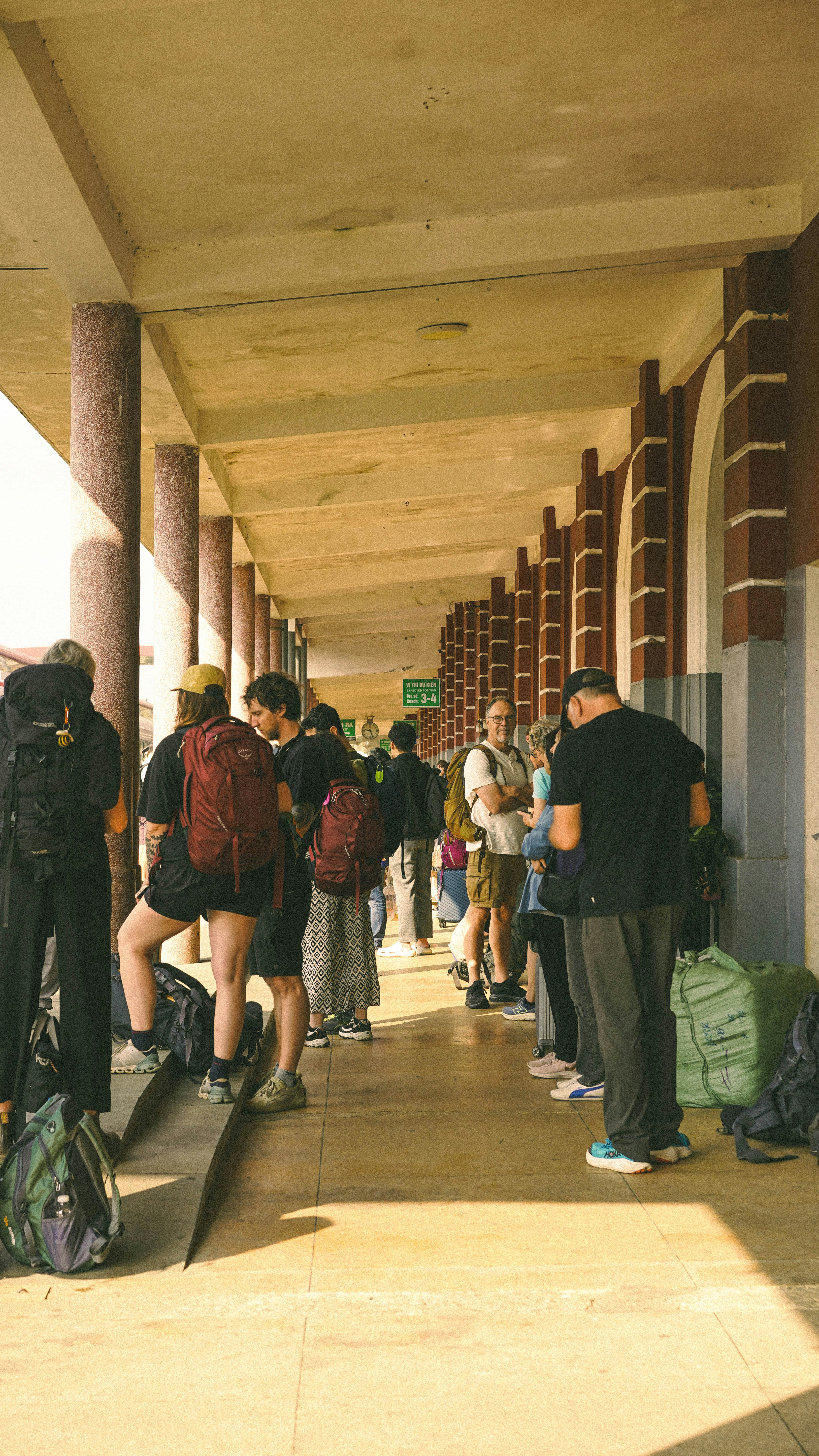 Travellers waiting in a covered walkway with backpacks — the moment before boarding when seat selection still matters