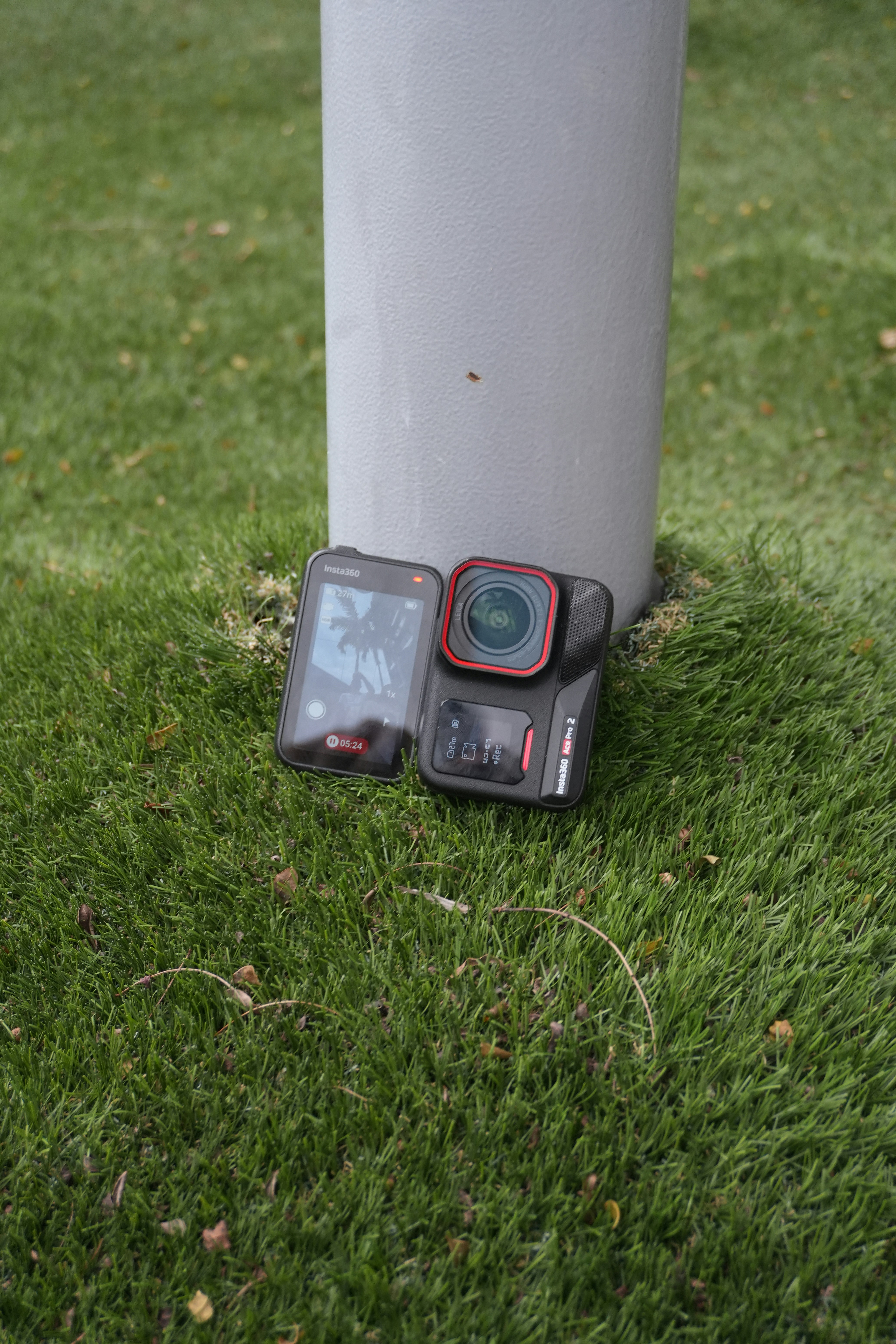 Action camera resting on grass next to pole